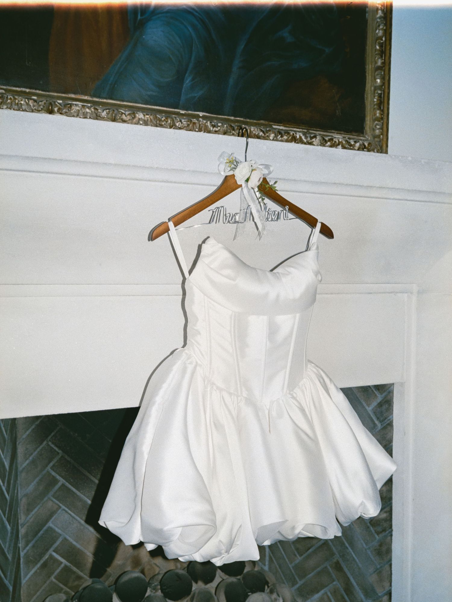 White sleeveless dress on wooden hangers displayed against a wall showing multiple angles of the garment.
