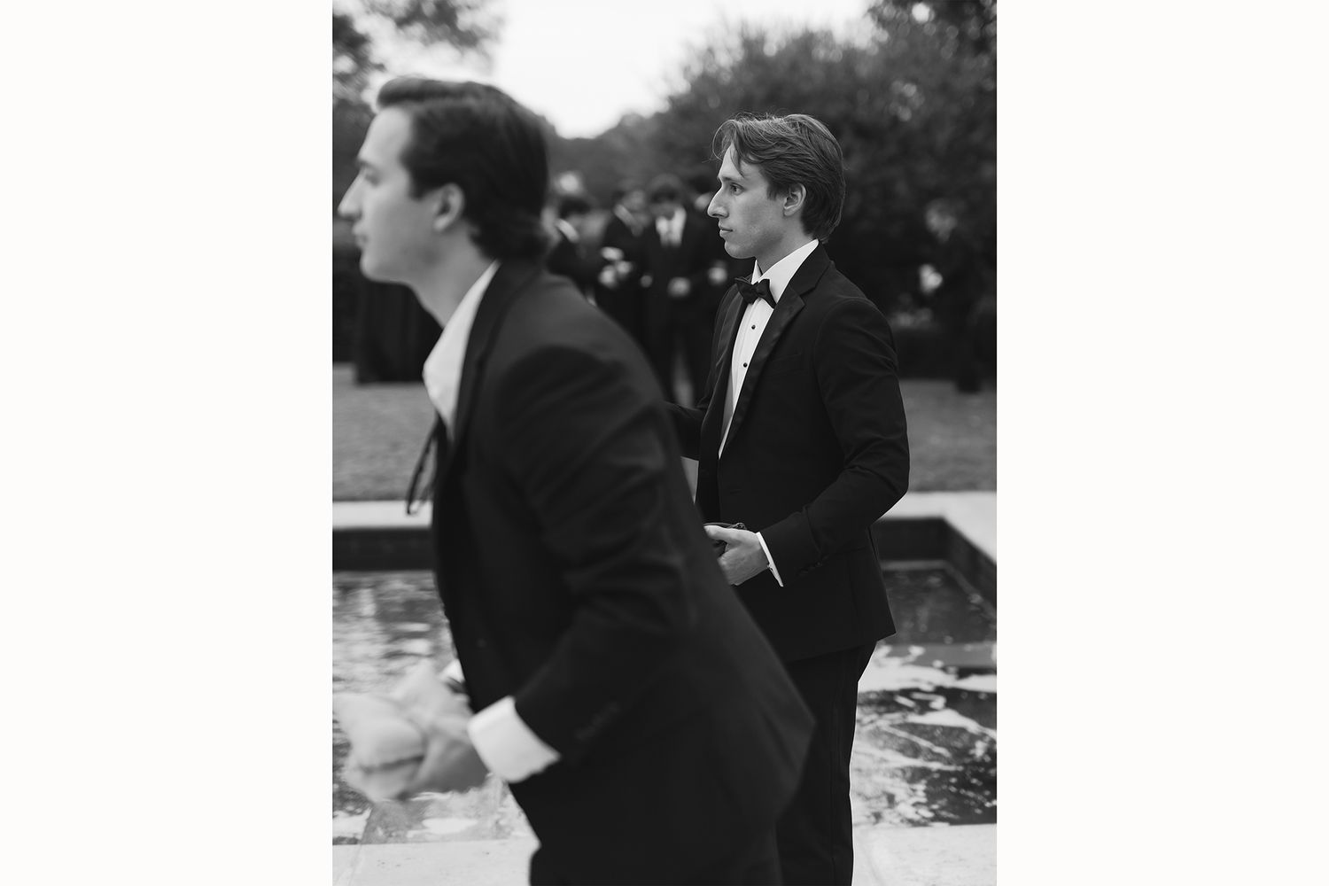 Two figures in dark coats having an animated conversation outdoors in black and white.