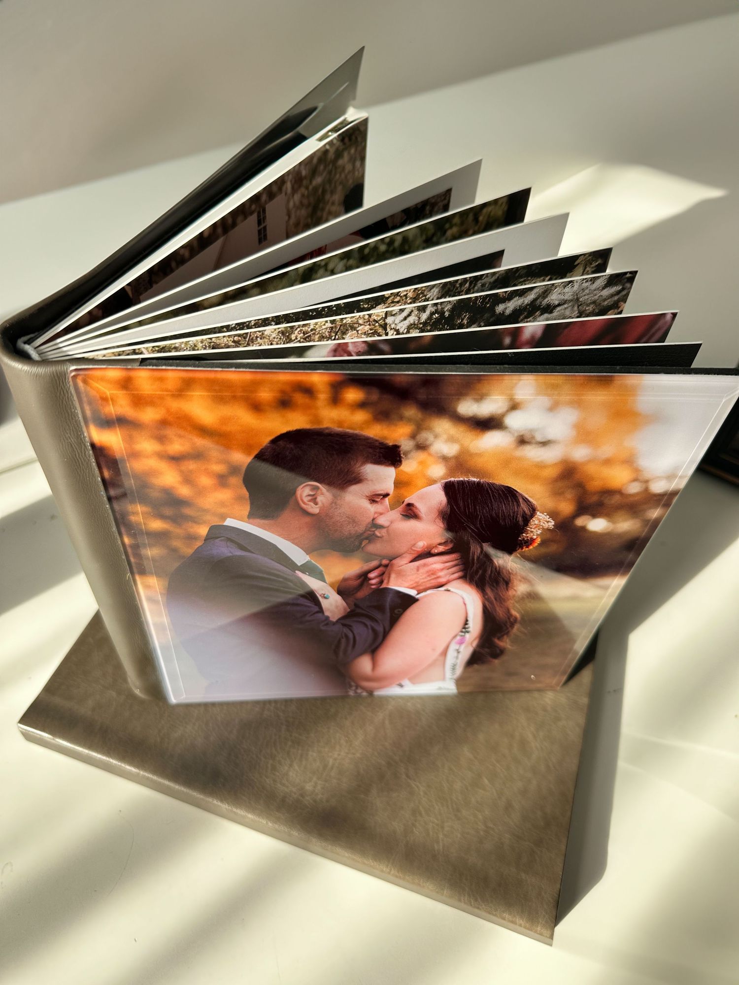 An open wedding photo album displaying romantic couple portraits.