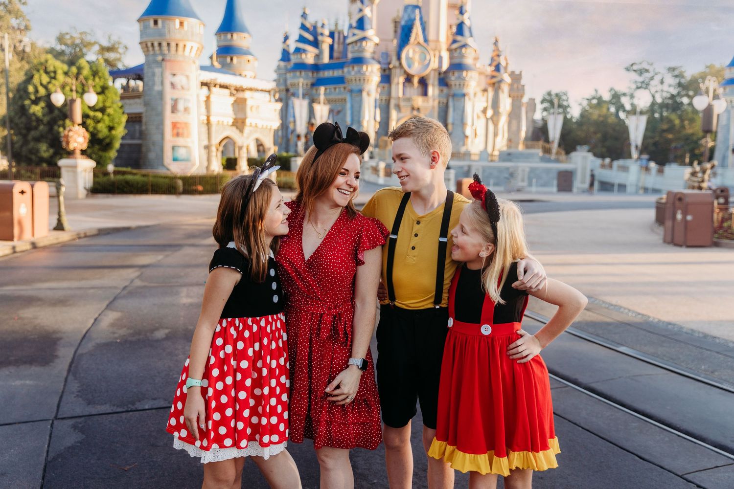 Family posing in Mickey Mouse outfits in front of Cinderella Castle at Walt Disney World Magic Kingdom.
