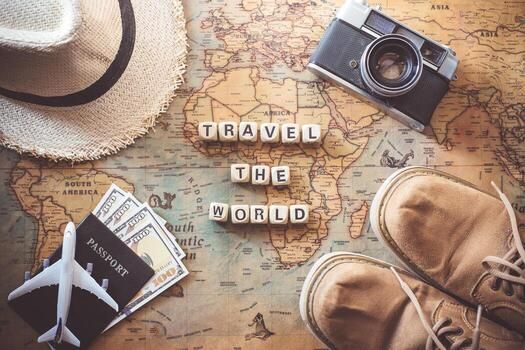 Travel planning flatlay with map, passport, camera, hat, shoes, and Travel The World letter tiles.
