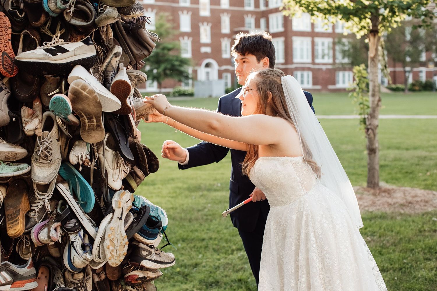 Wedding guests toss their shoes in the air while posing for a fun group photo outdoors.