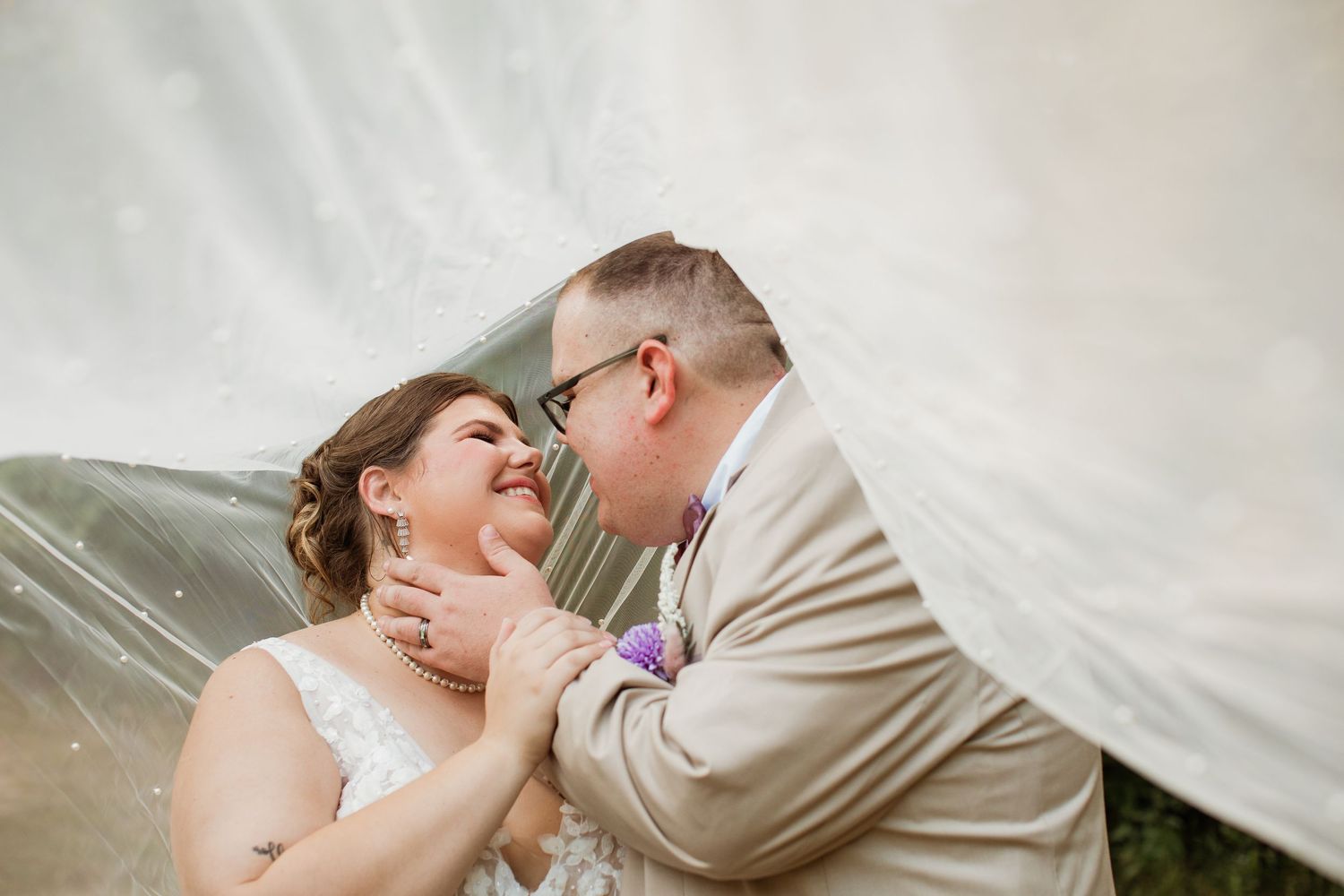 A romantic moment shared between a couple in formal wedding attire under soft lighting.