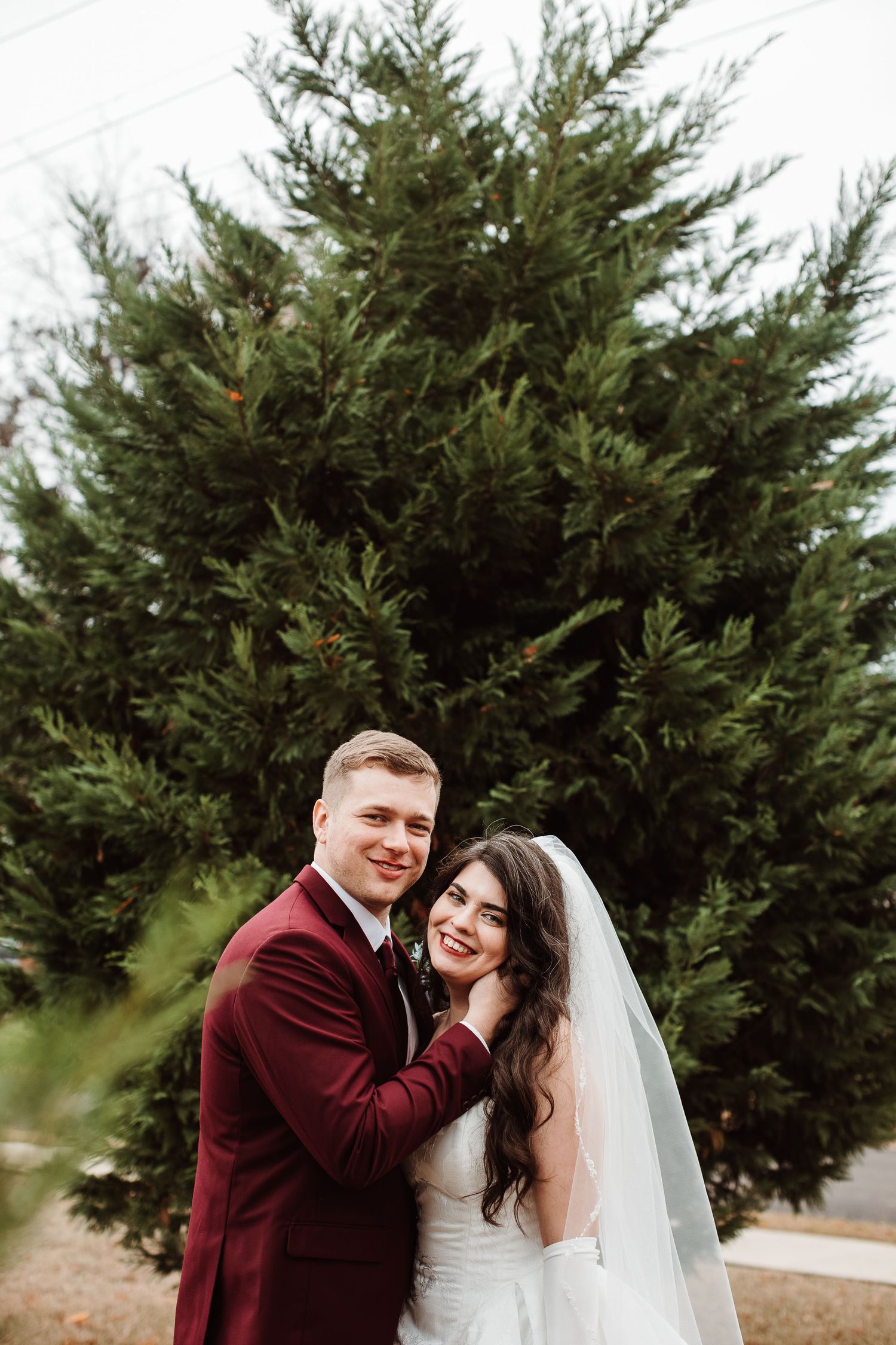 A couple shares joyful moments together among evergreen trees during their winter wedding celebration.