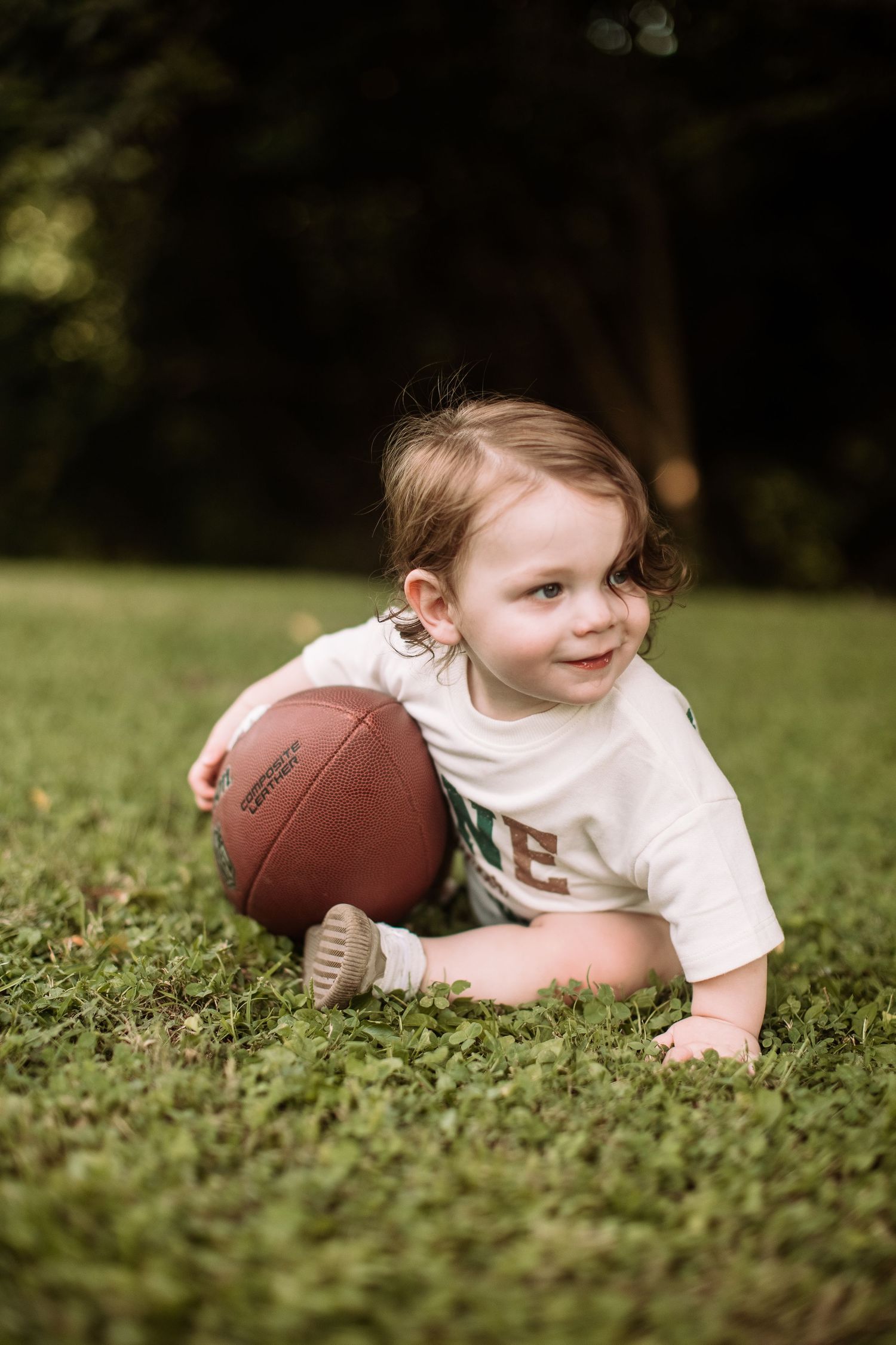 A small child lies in grass while playing with a football in a series of progressive action shots.