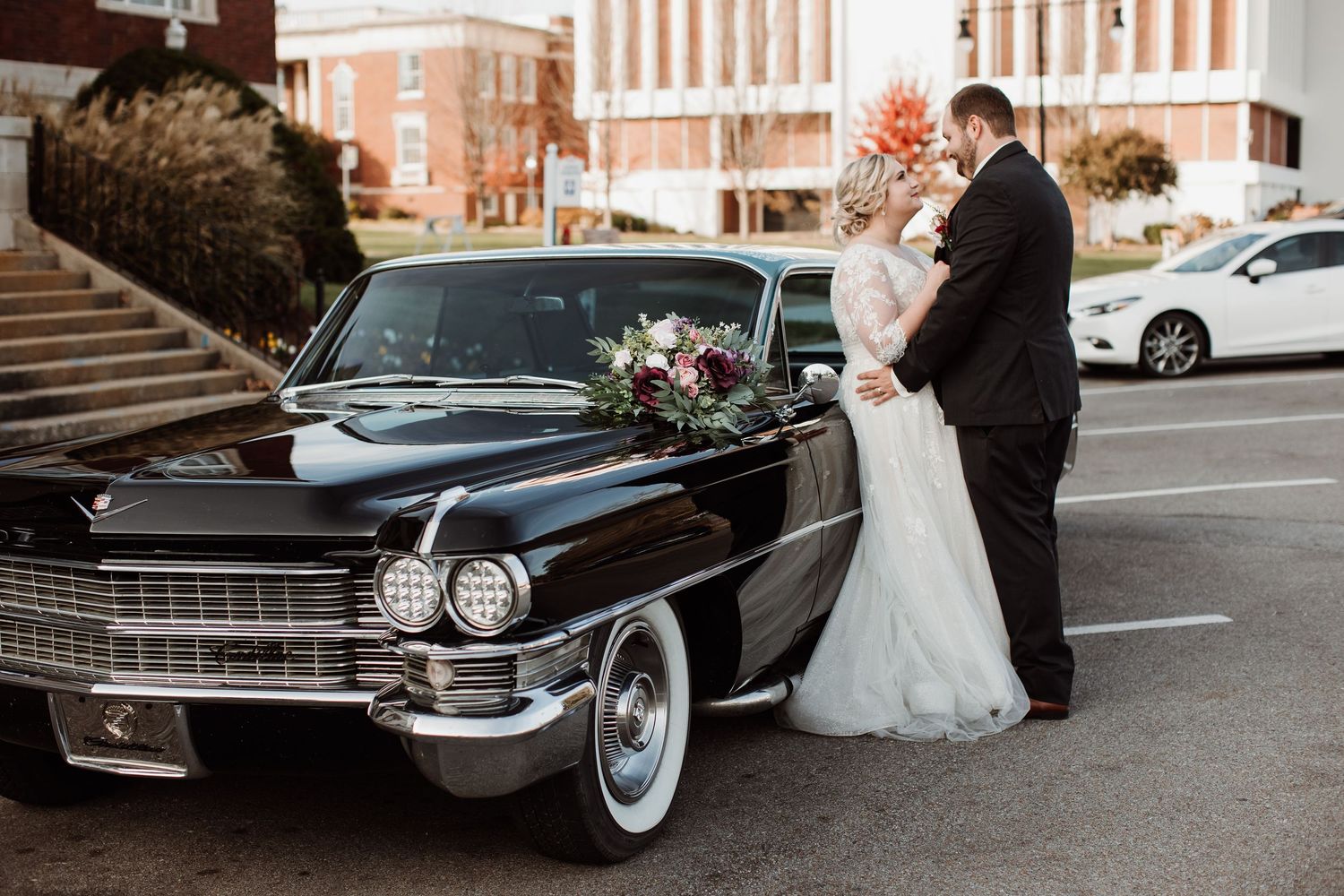 Classic black Cadillac wedding car parked outside brick building with elegant decorative details.