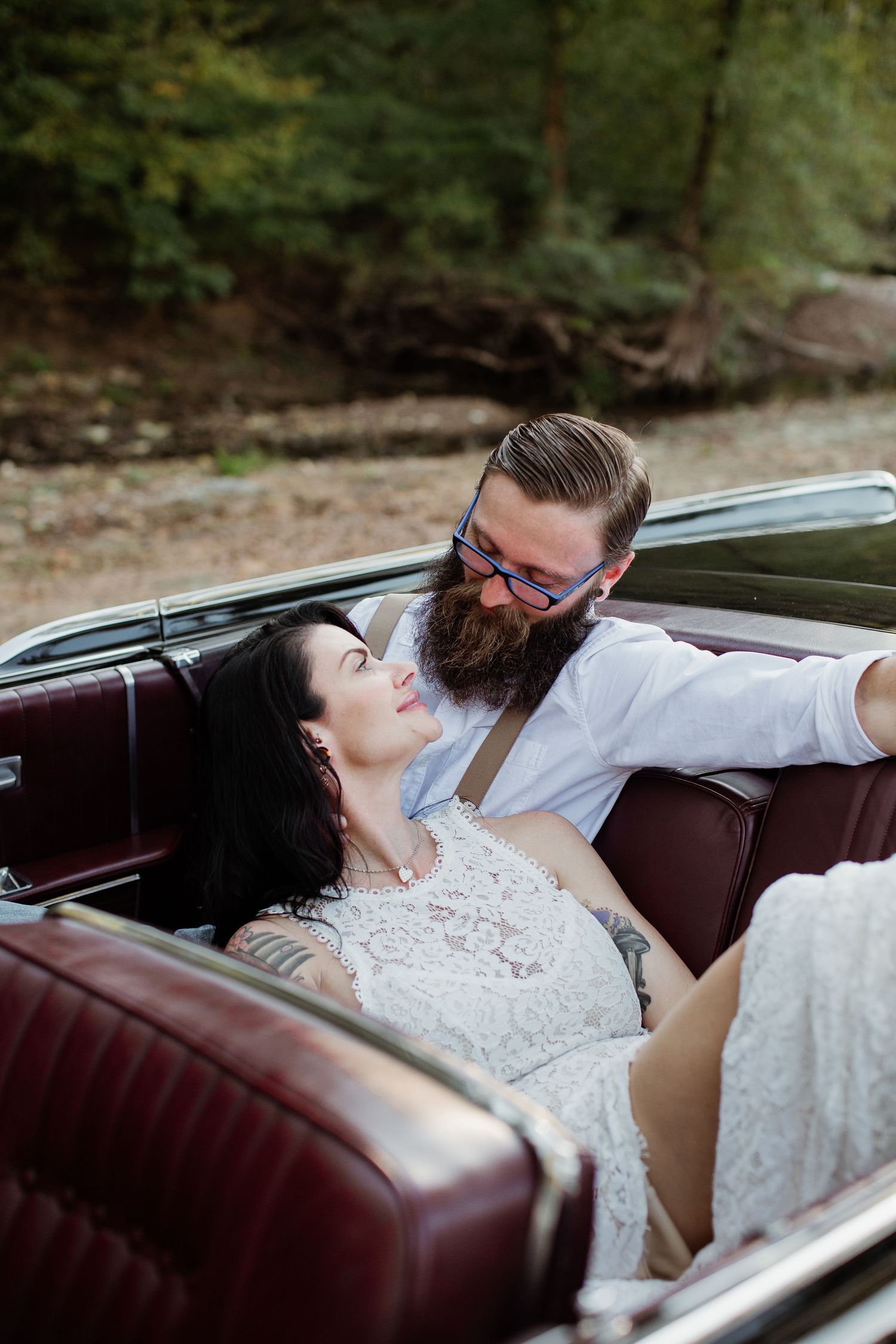 A couple shares an intimate moment while reclining in a vintage car with brown leather seats.