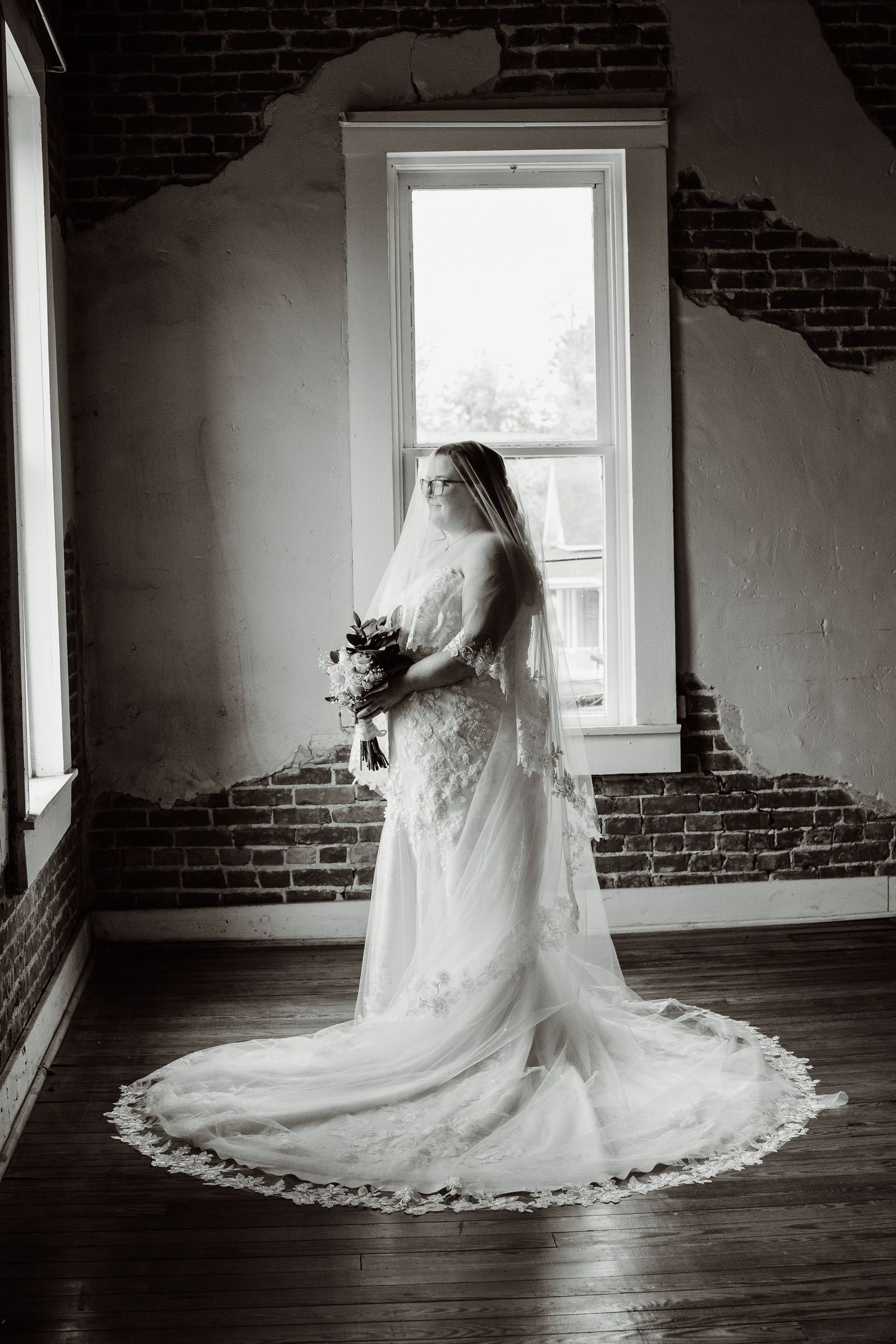 Black and white photo series showing a flowing white wedding dress arranged in different poses on a hardwood floor.
