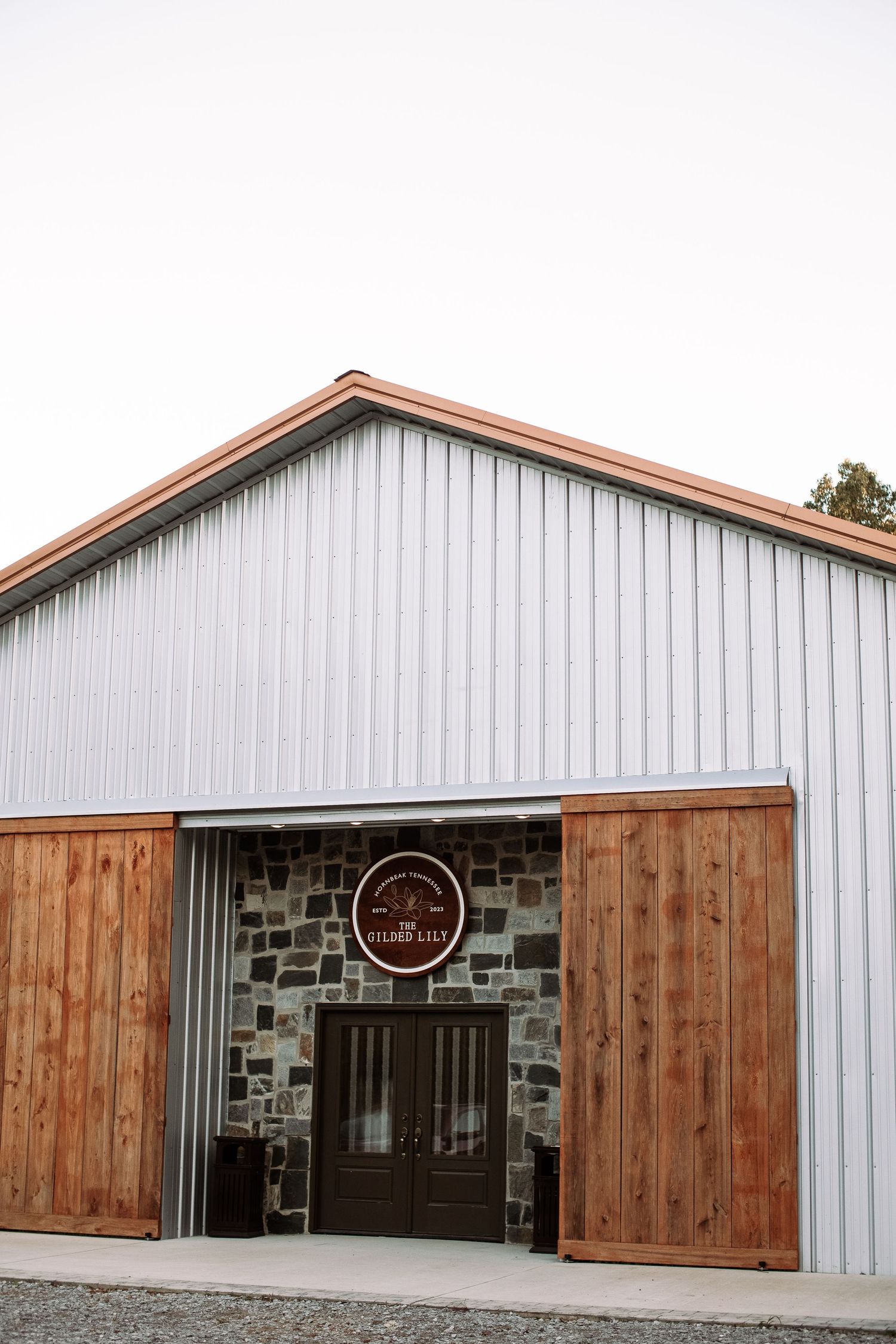 Modern barn-style building exterior with stone accents, wooden sliding doors, and metal siding panels.