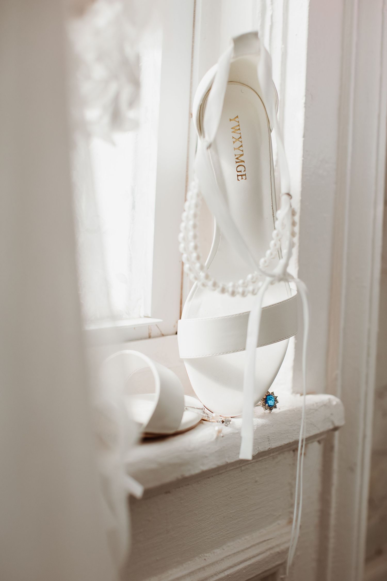 White curtains gently billow in sunlight near a window sill with delicate decor details.