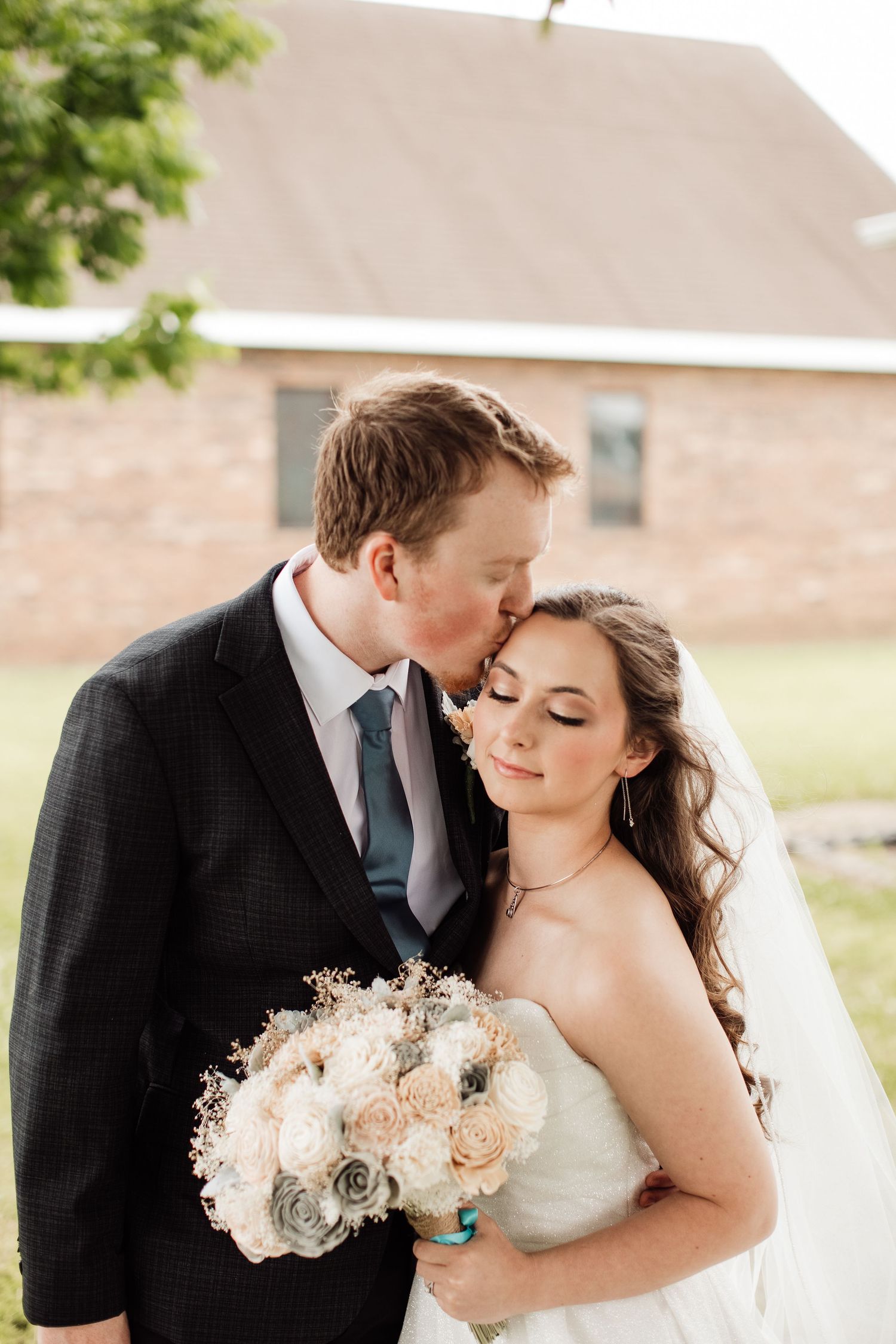 A romantic wedding couple shares tender moments in a series of outdoor portraits with soft blush rose bouquets.