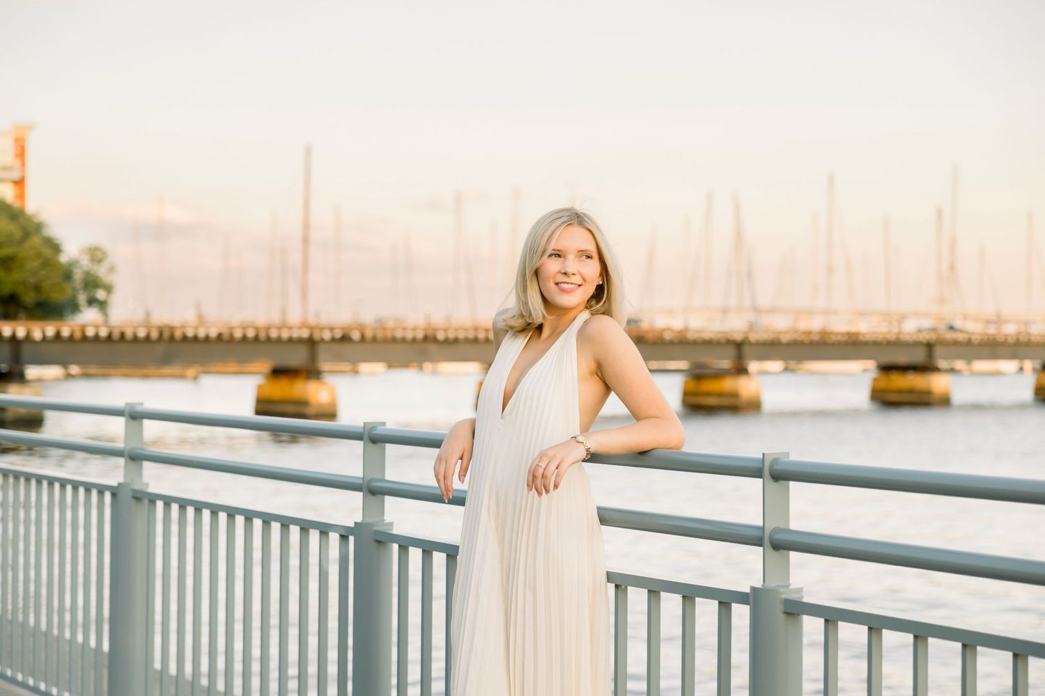 Golden hour photography session on a waterfront deck with sailboats in the distance.
