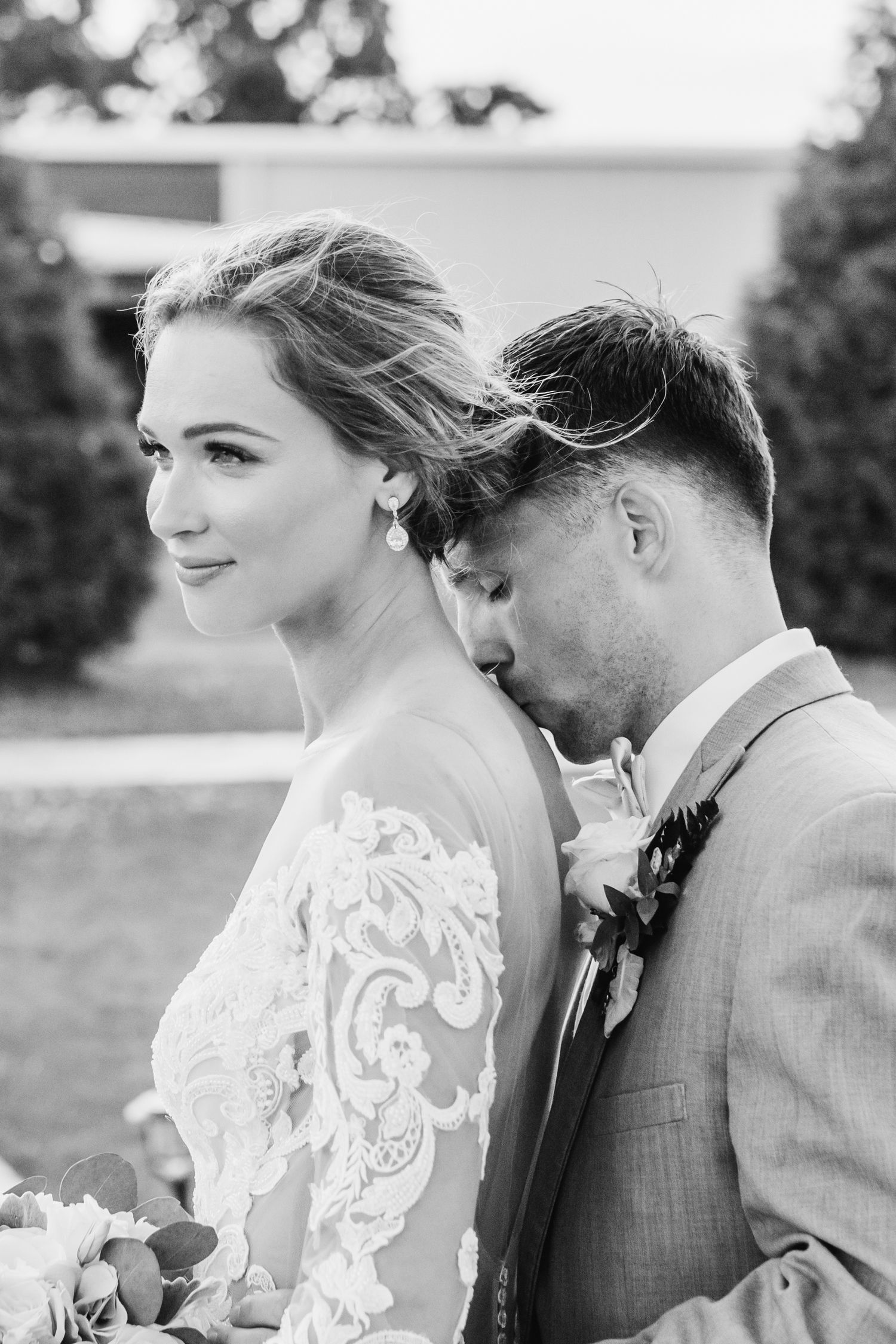 Intimate black and white wedding portrait captures romantic moment outdoors.
