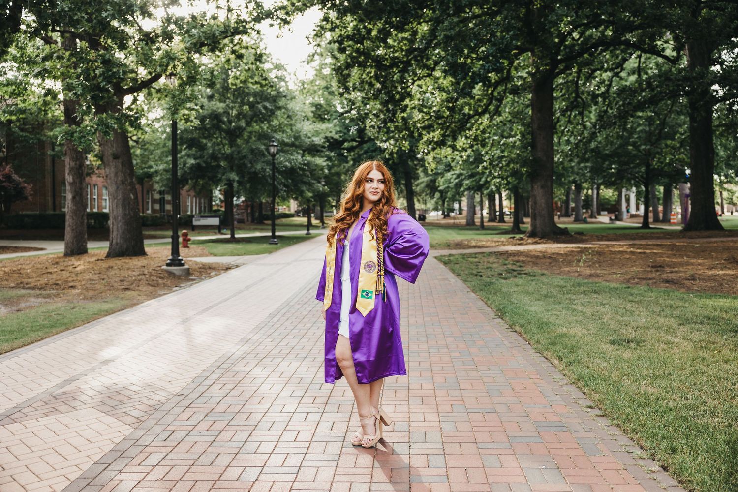 Person in purple jacket walking along brick pathway through tree-lined park.