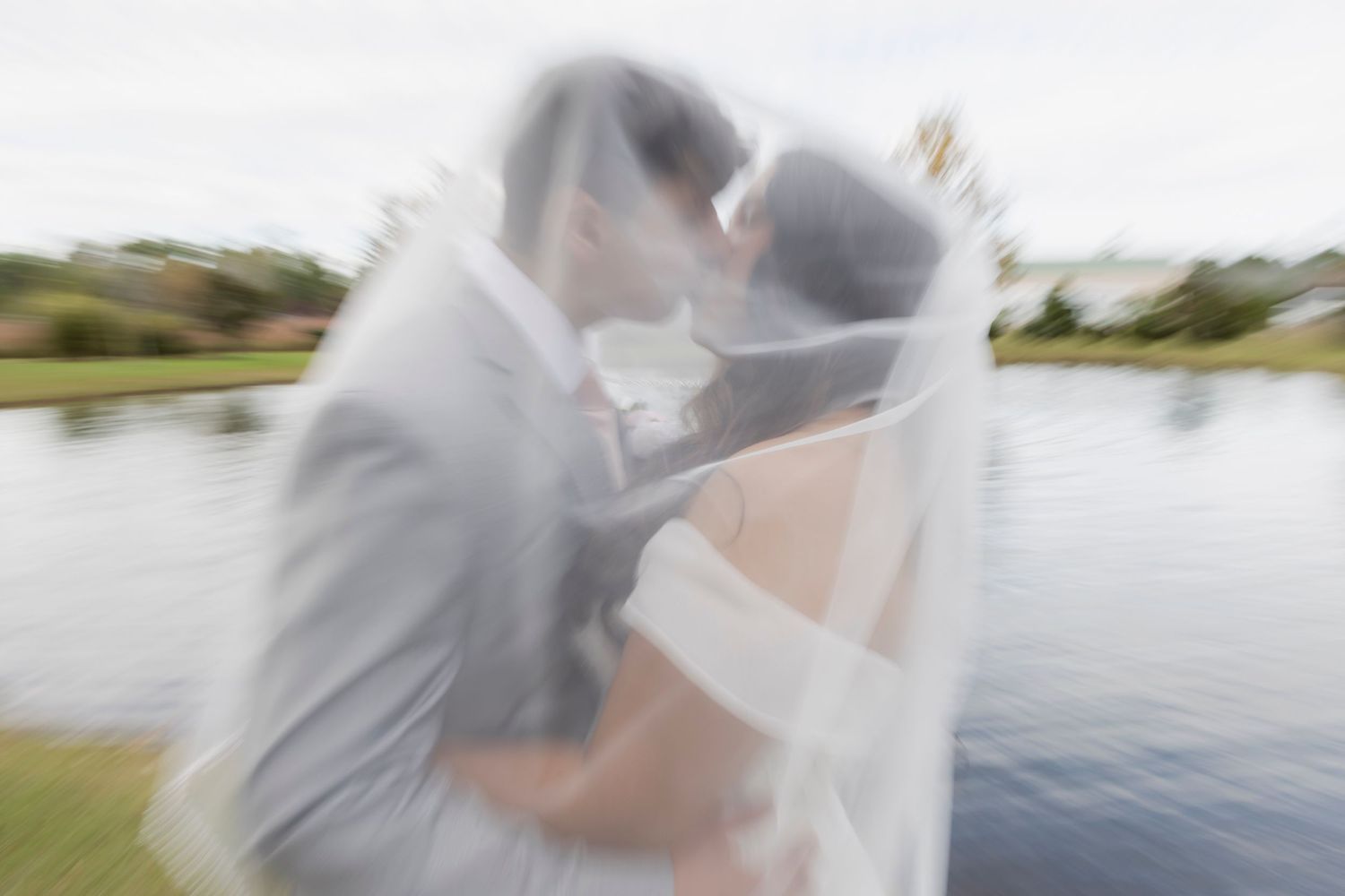 Intimate waterfront photo session with flowing veil creating ethereal effects.