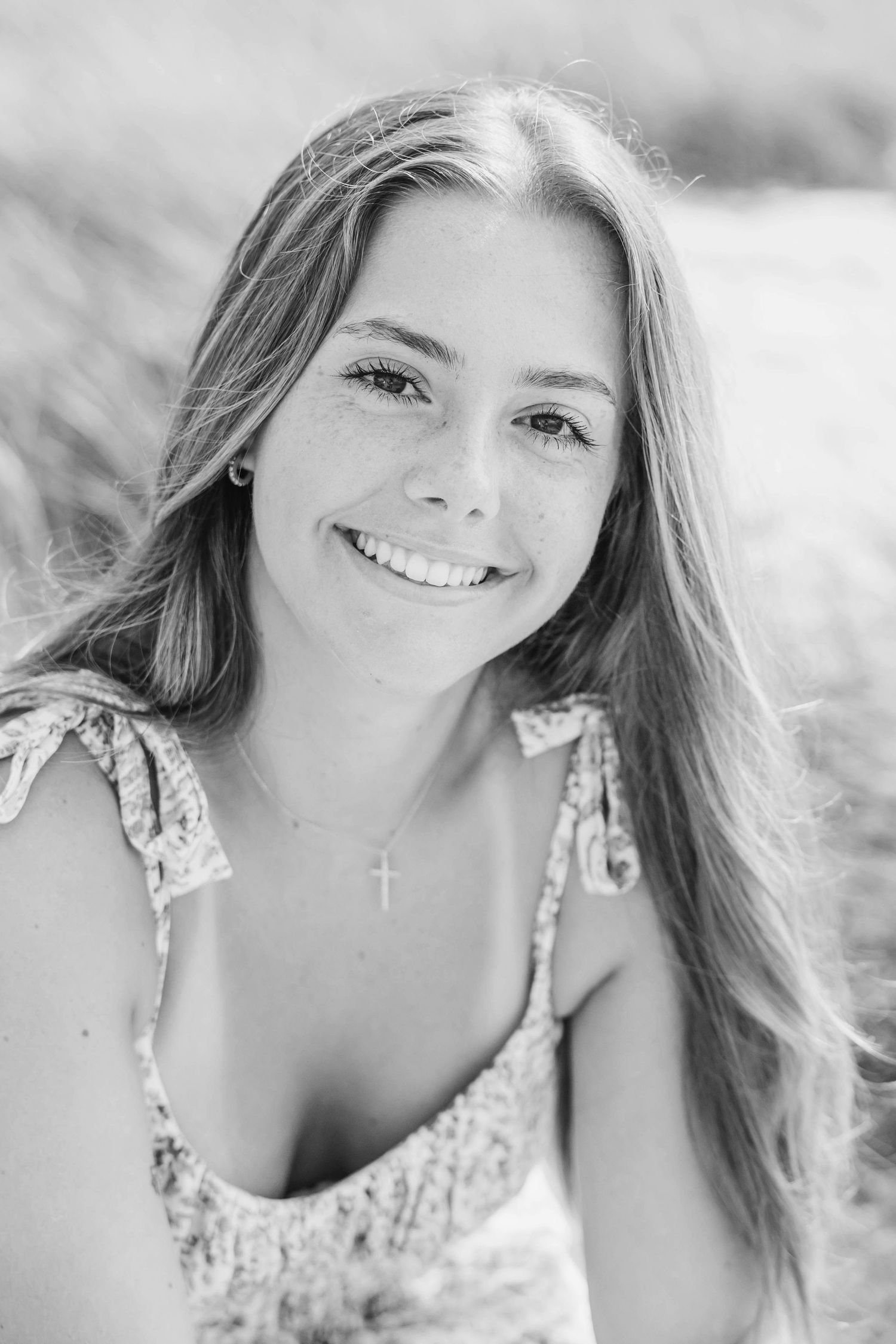 Black and white portrait series of a woman in a floral dress smiling outdoors.
