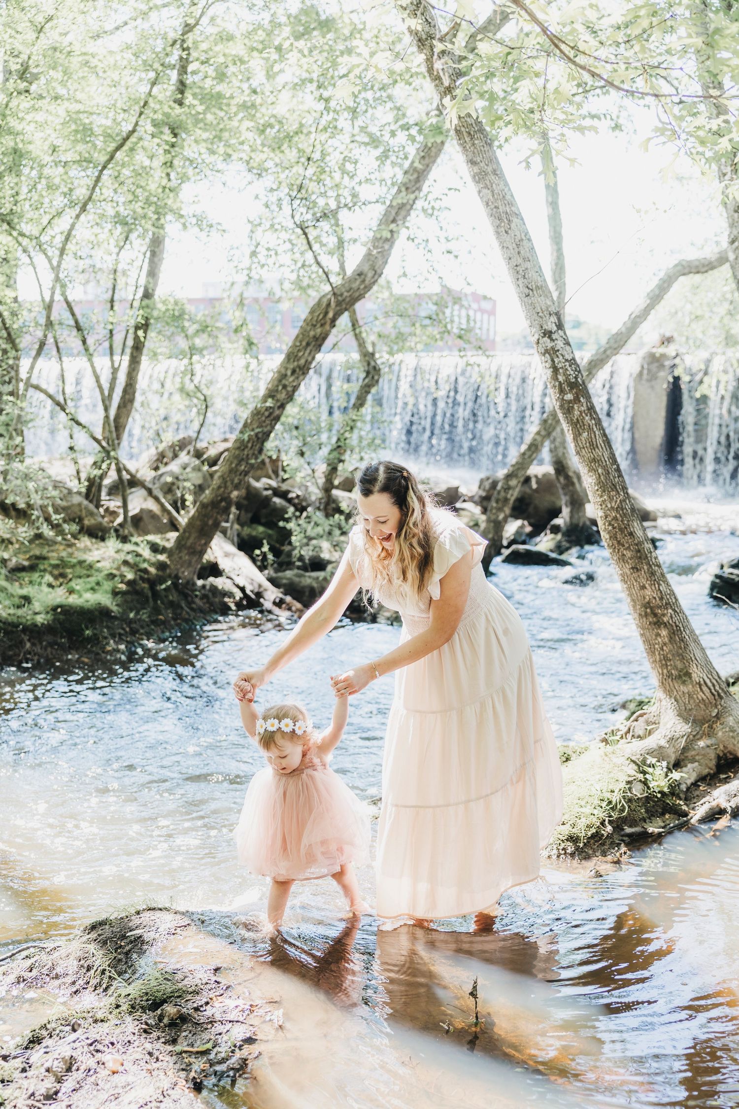 A tender moment captured by a waterfall as two figures play in the shallow stream.