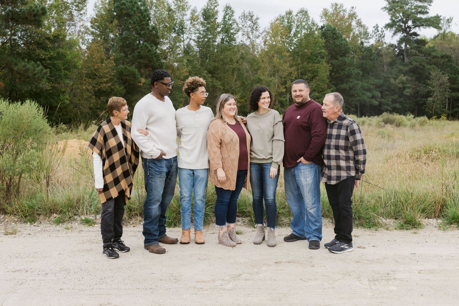 A group of people standing together in a casual outdoor setting against a natural backdrop.