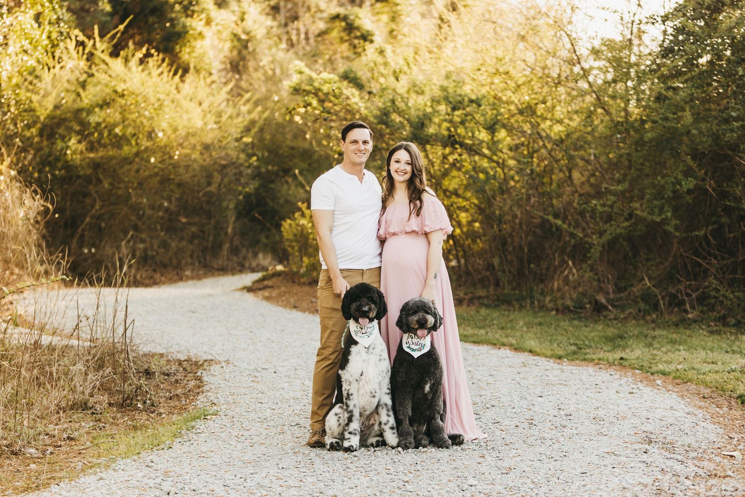 Family and pets pose together on gravel path during sunset outdoor photo session.