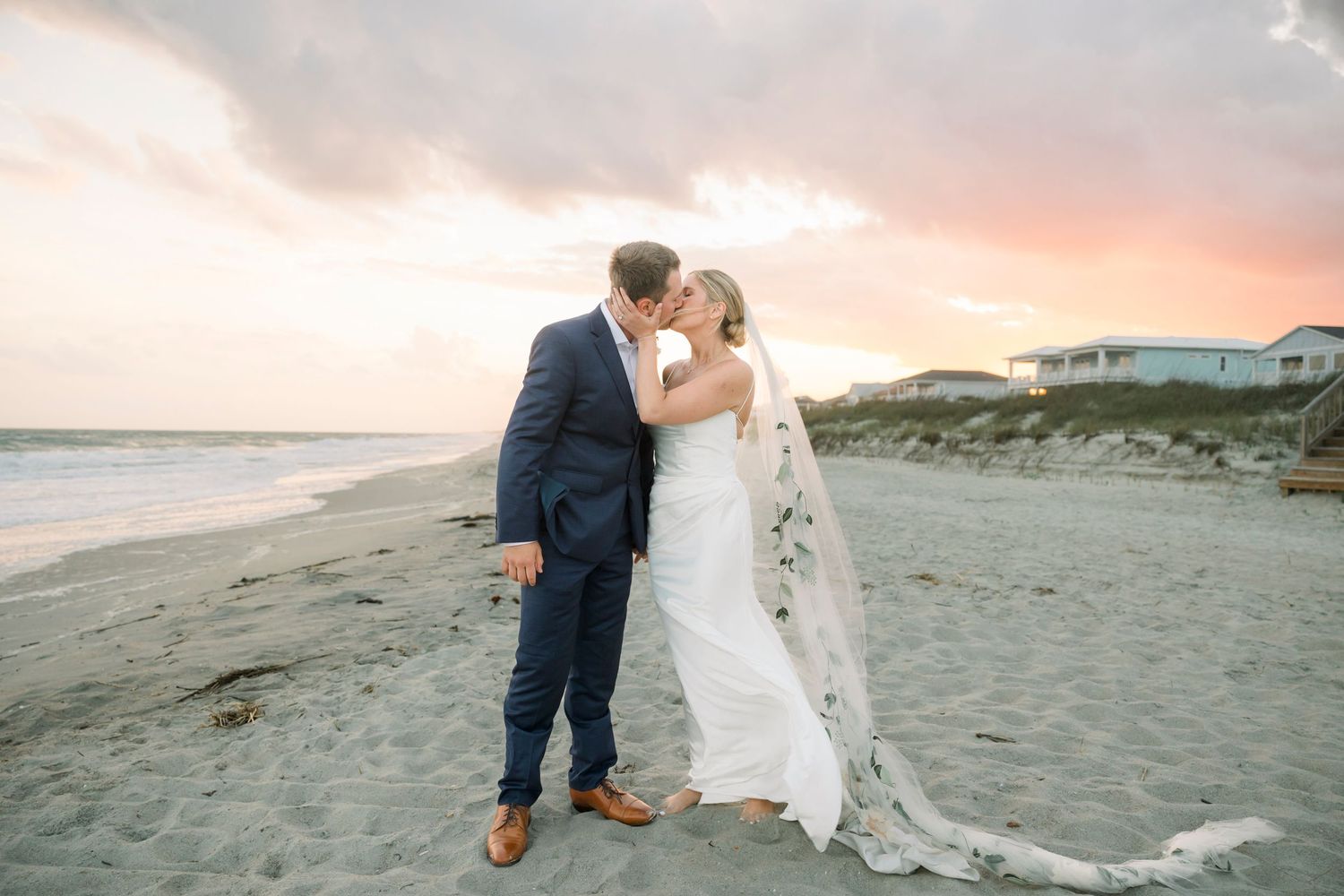 Newlyweds sharing intimate moments on sandy beach during golden hour.