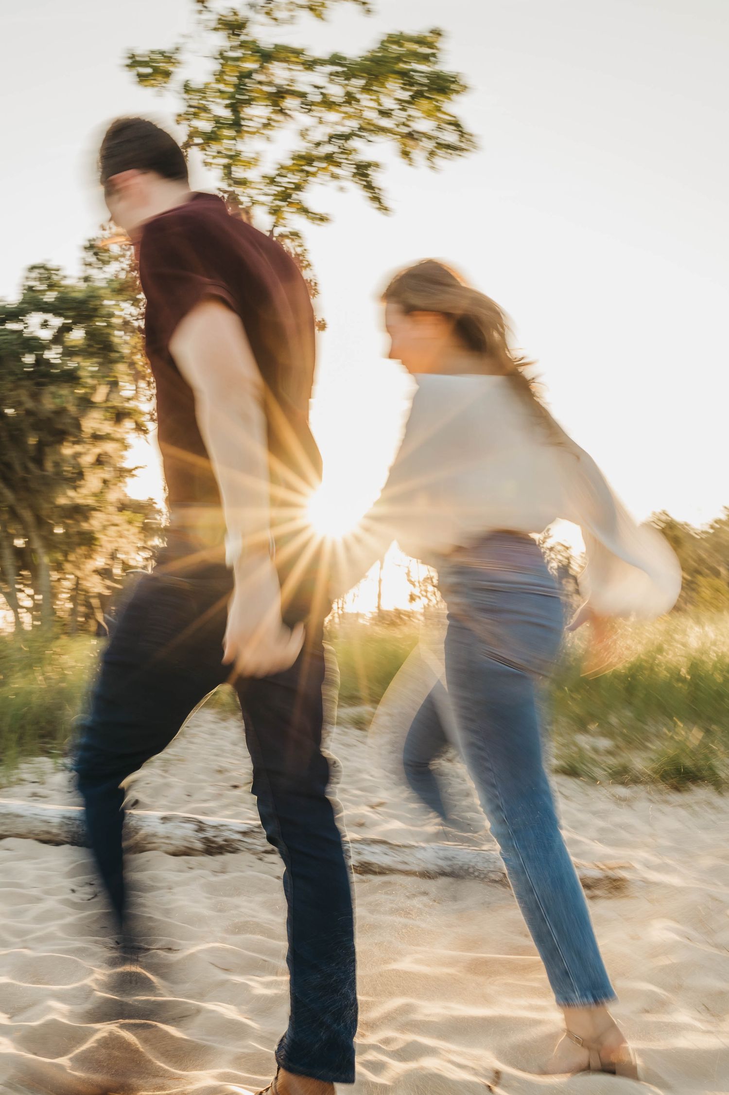 Motion blur photography of people dancing on a sandy beach at sunset.