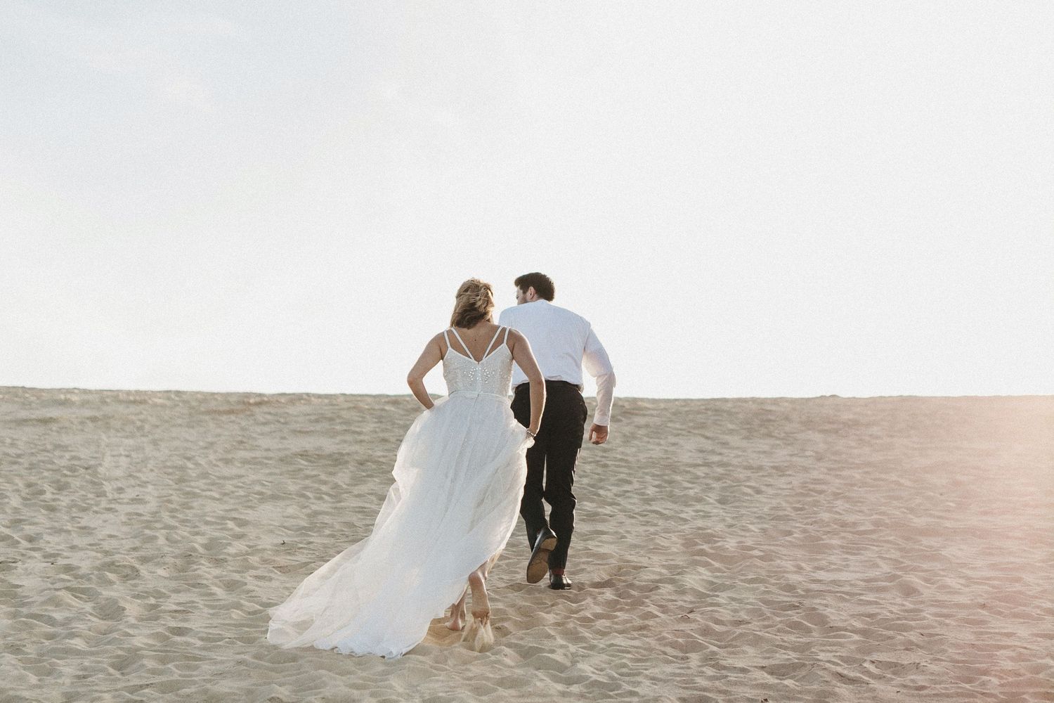 Couple walking along a sandy beach during a sunset photo session.