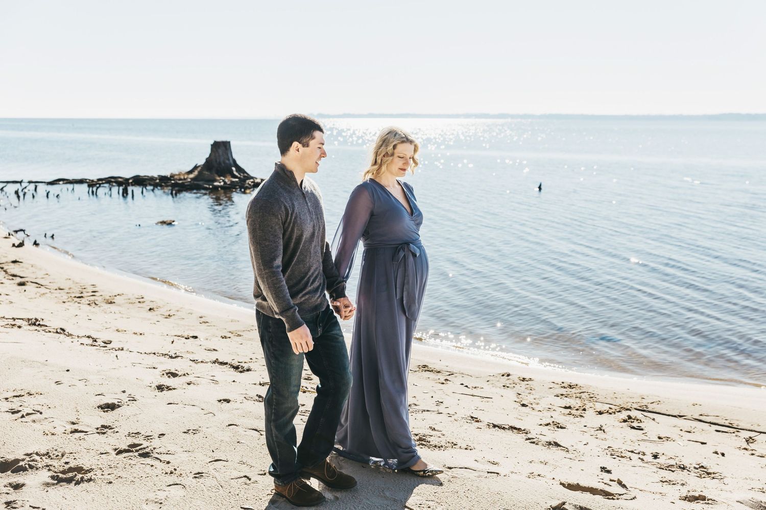 Couple walks along peaceful beach shoreline during cloudy day photo session.