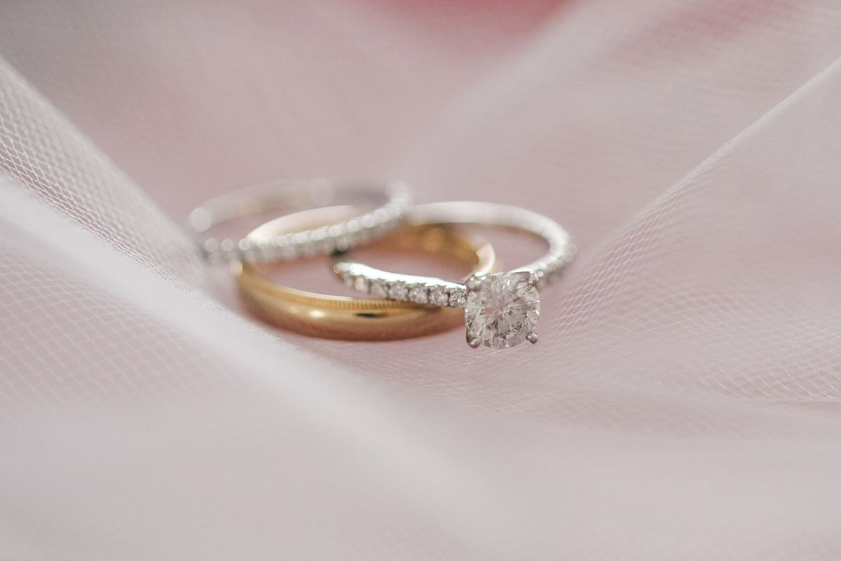 Close-up macro shots of wedding rings and jewelry on pink fabric.