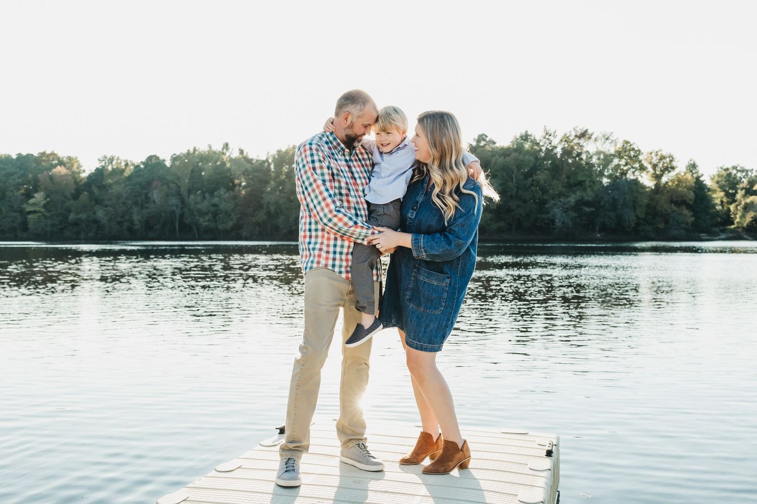 Family enjoying tender moments by serene lakeside at sunset.