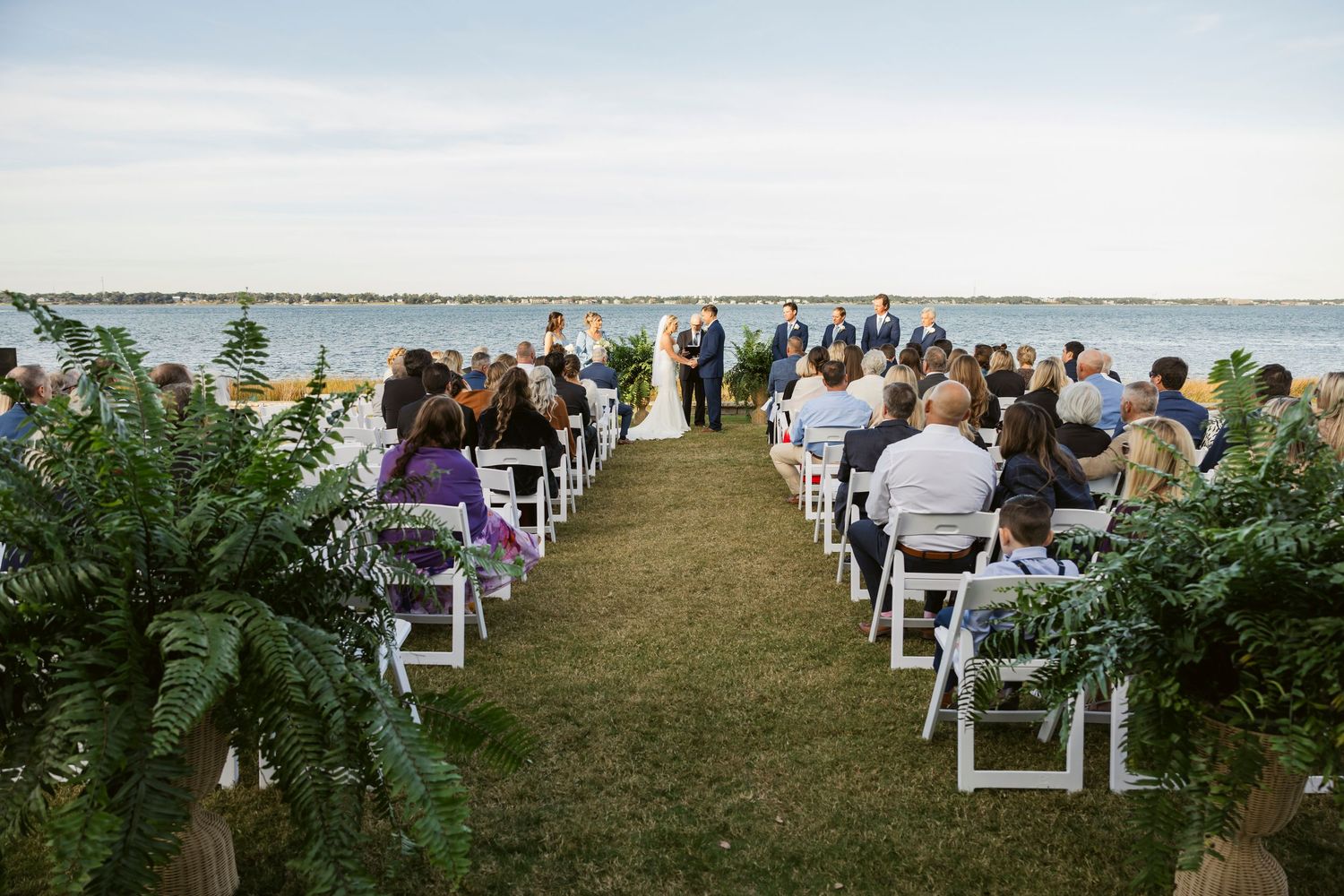 Waterfront wedding ceremony setup with white chairs overlooking a serene lake.