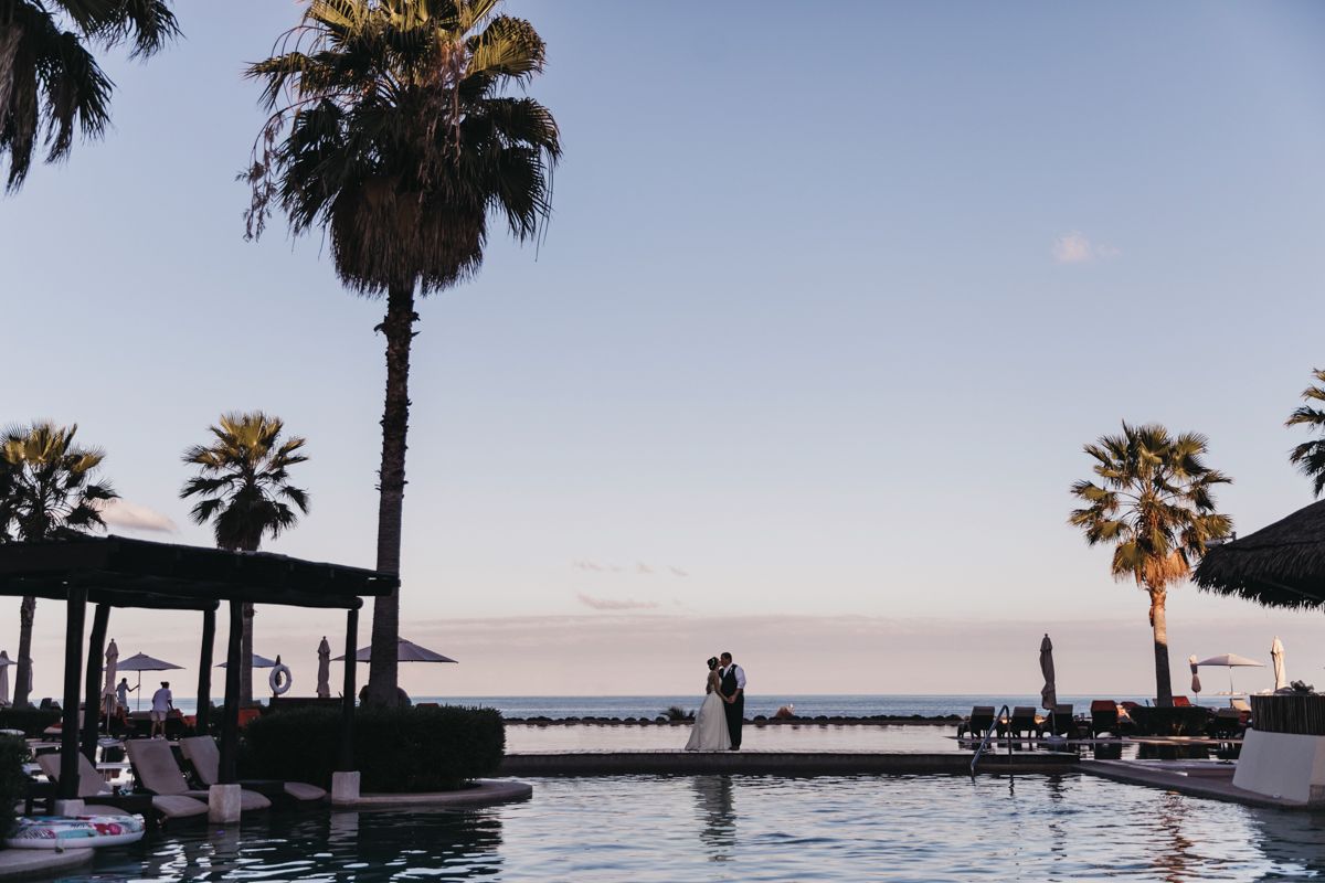 Palm trees silhouetted against sunset sky at tropical beach wedding venue.