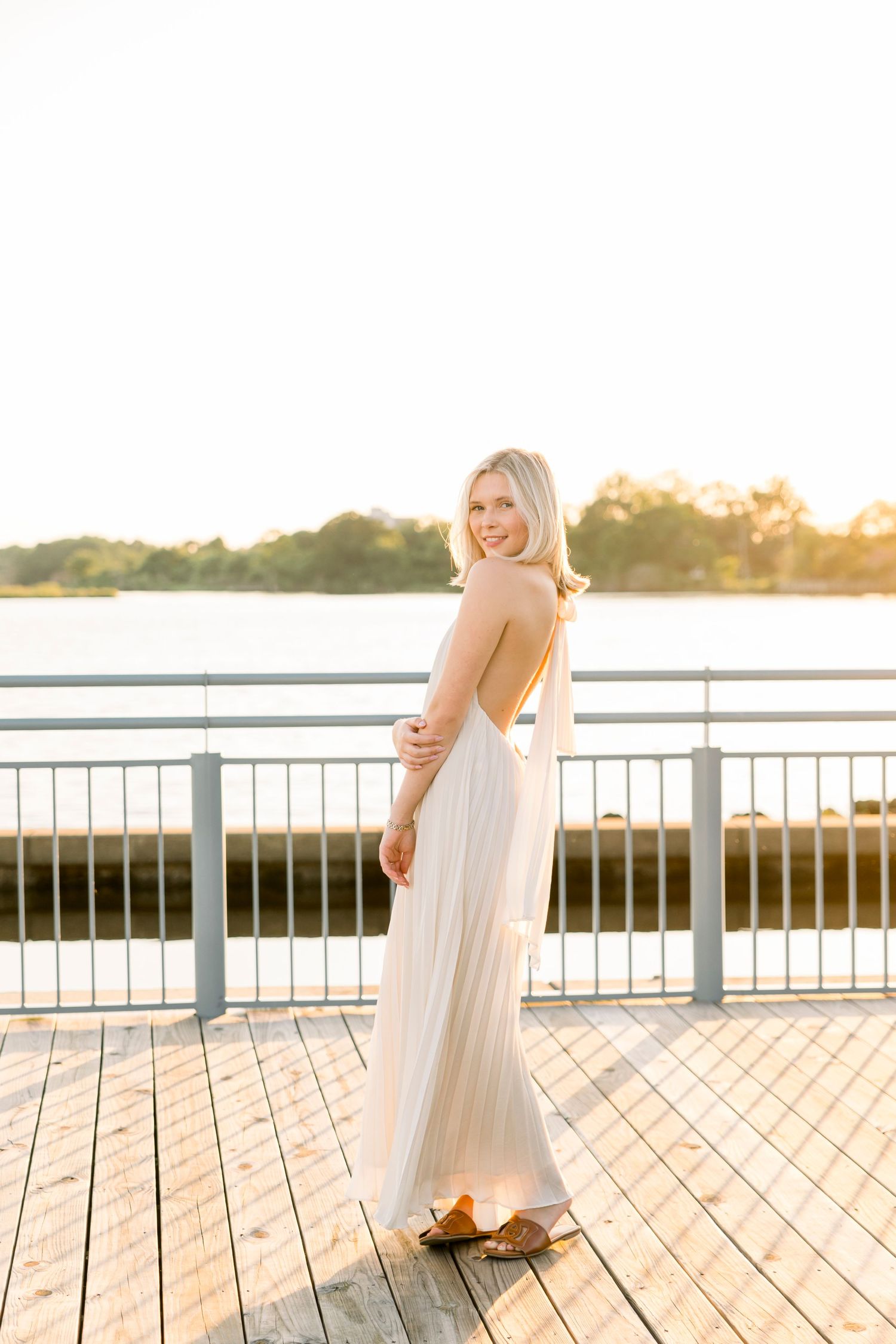 Sunset photoshoot on a wooden dock overlooking a serene waterfront.