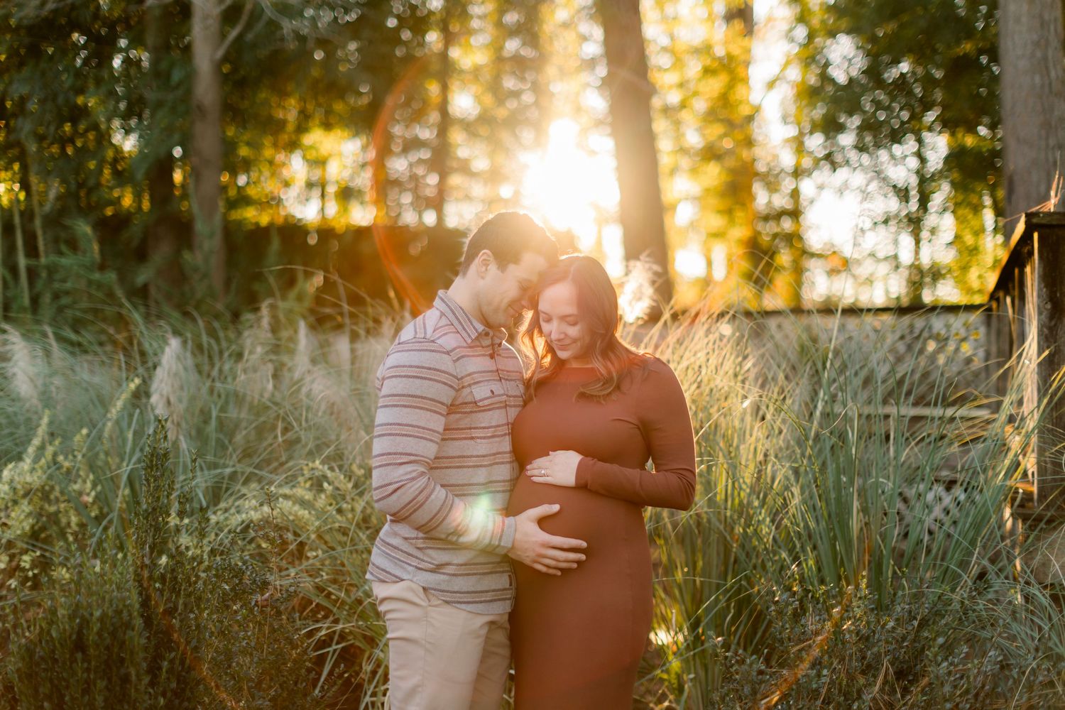 Golden hour maternity photos captured in a serene outdoor setting with sunlight filtering through trees.