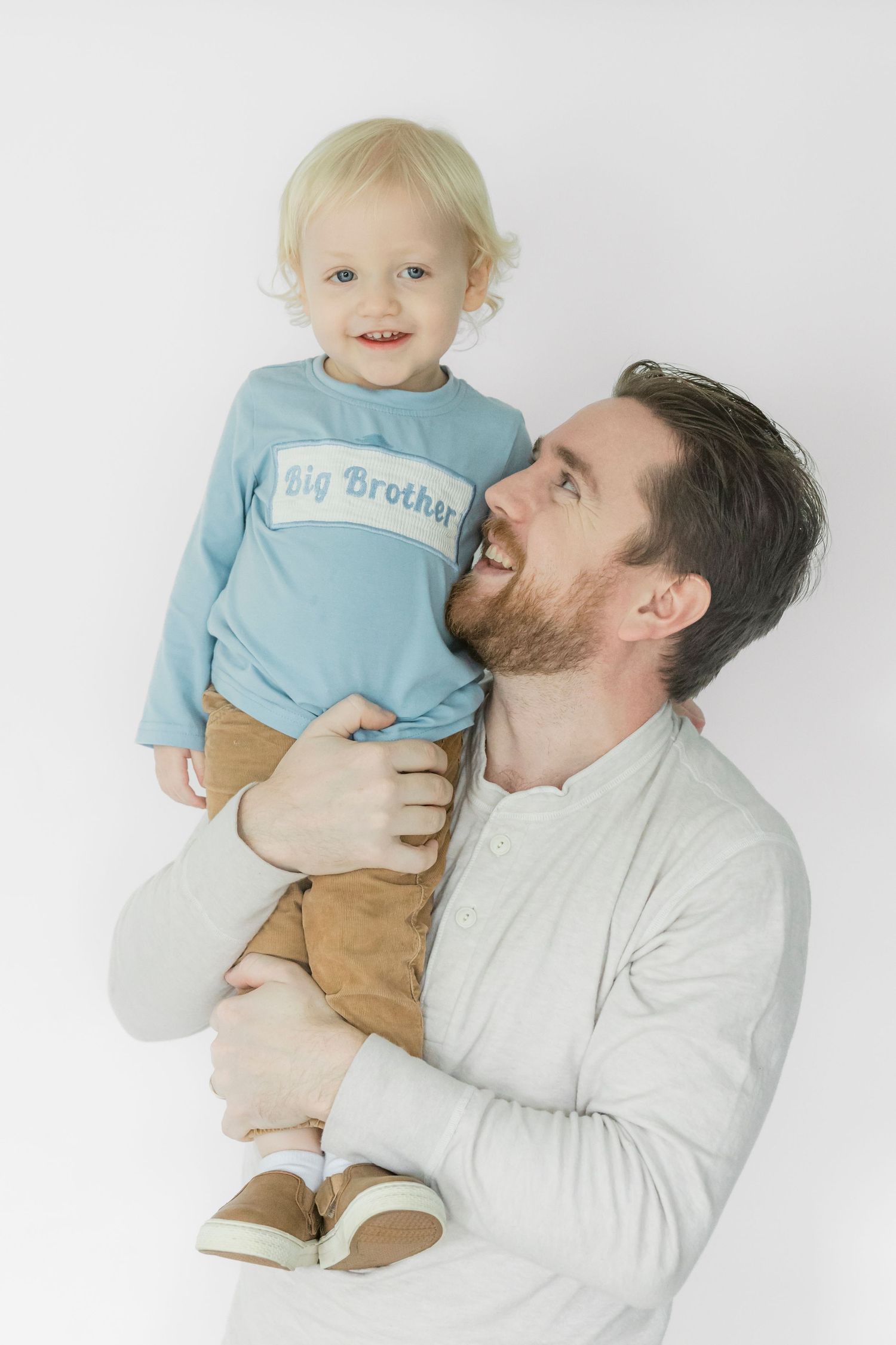 Sweet candid moments between a child in blue and an adult in white against a bright background.