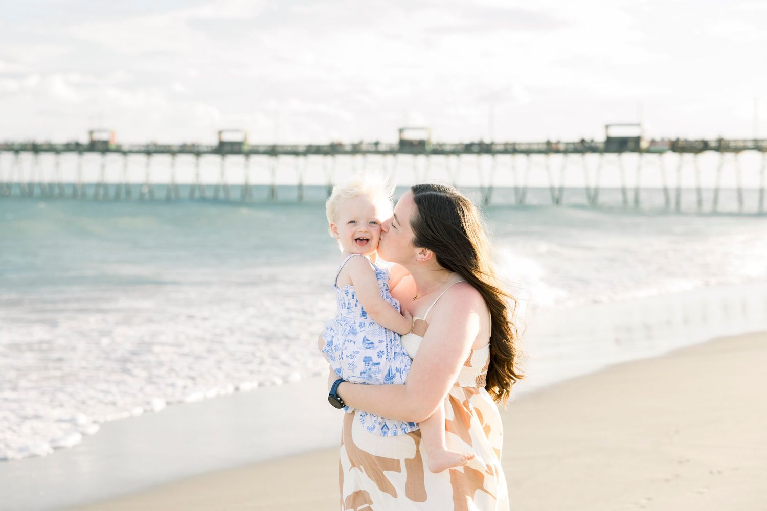Romantic pregnancy announcement photoshoot on sunny beach with waves.