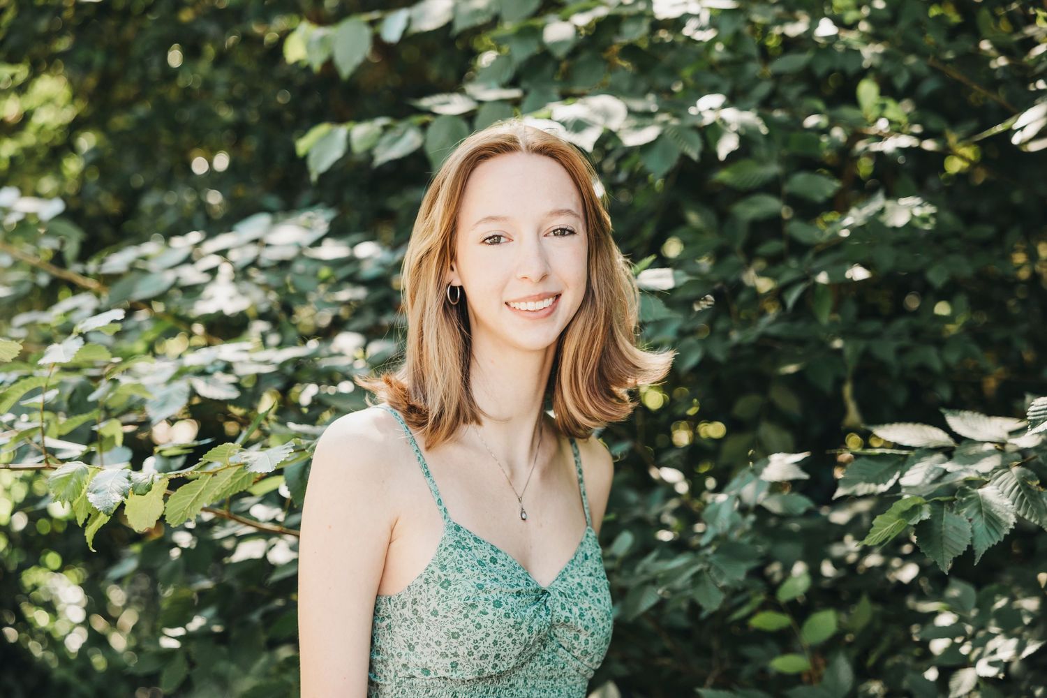 Natural light portrait session among leafy green foliage on a bright summer day.