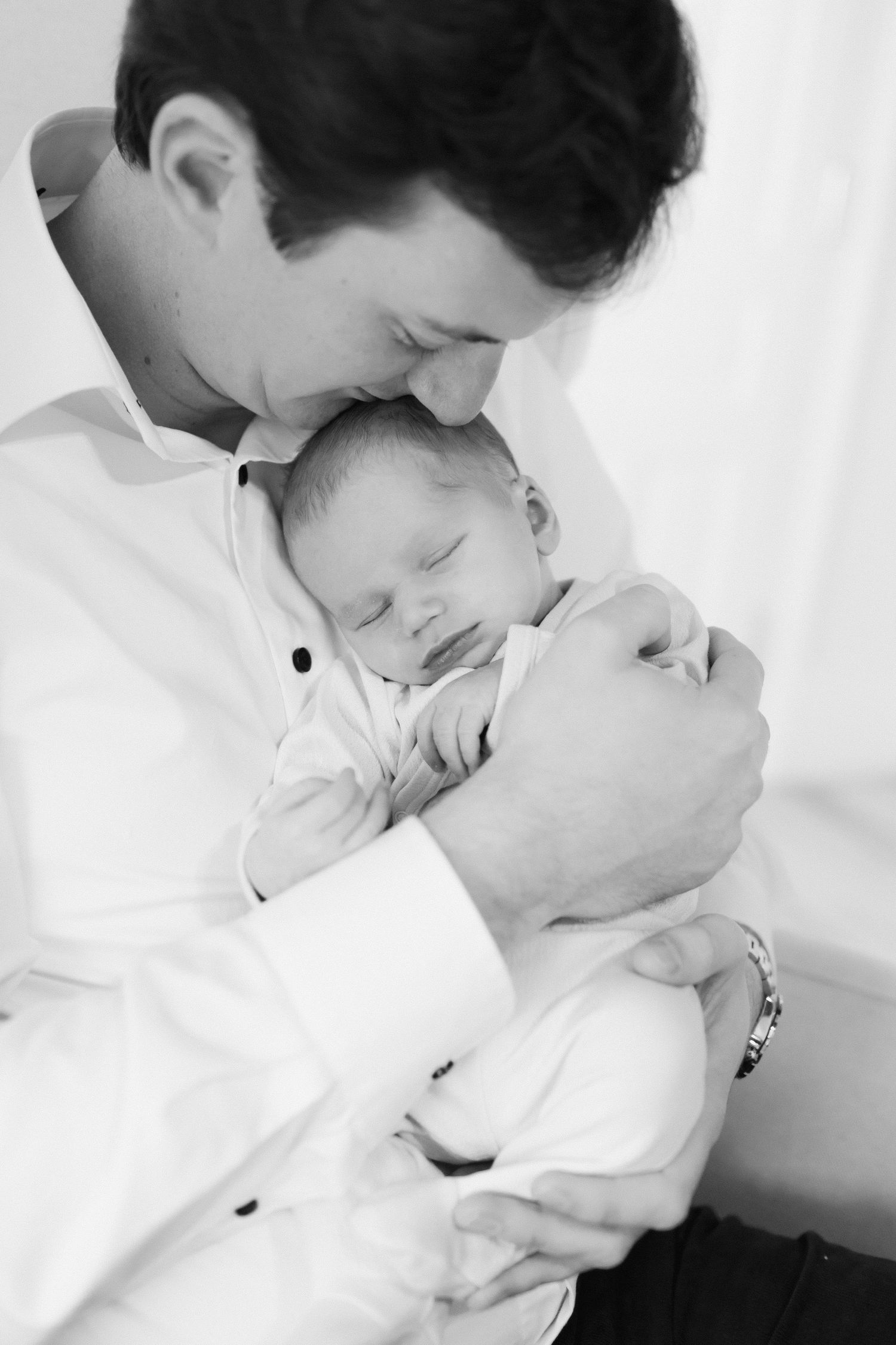 Intimate black and white portrait of tender moment with sleeping newborn.