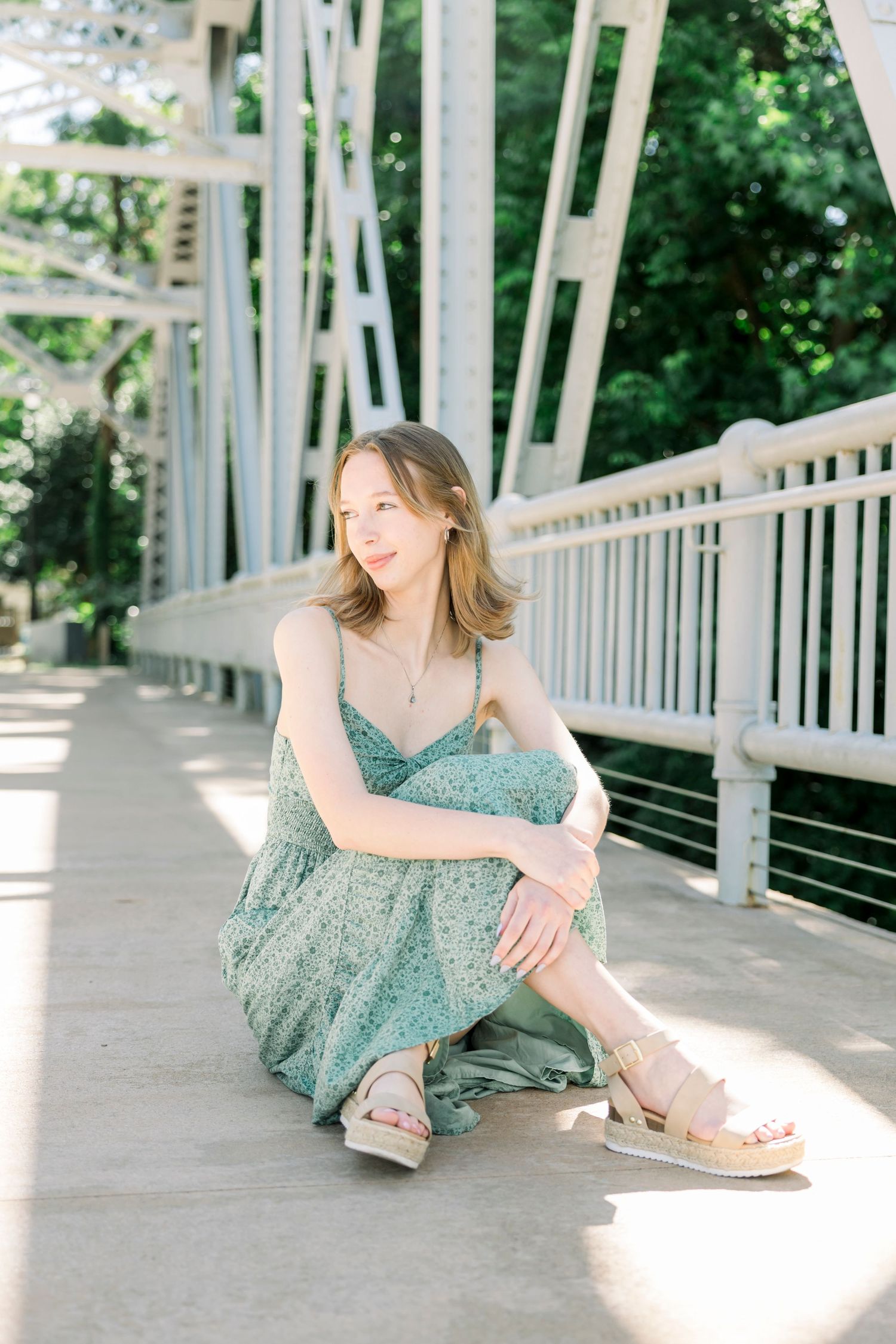 Summer photoshoot on a white architectural bridge with dappled sunlight creating dramatic shadows.
