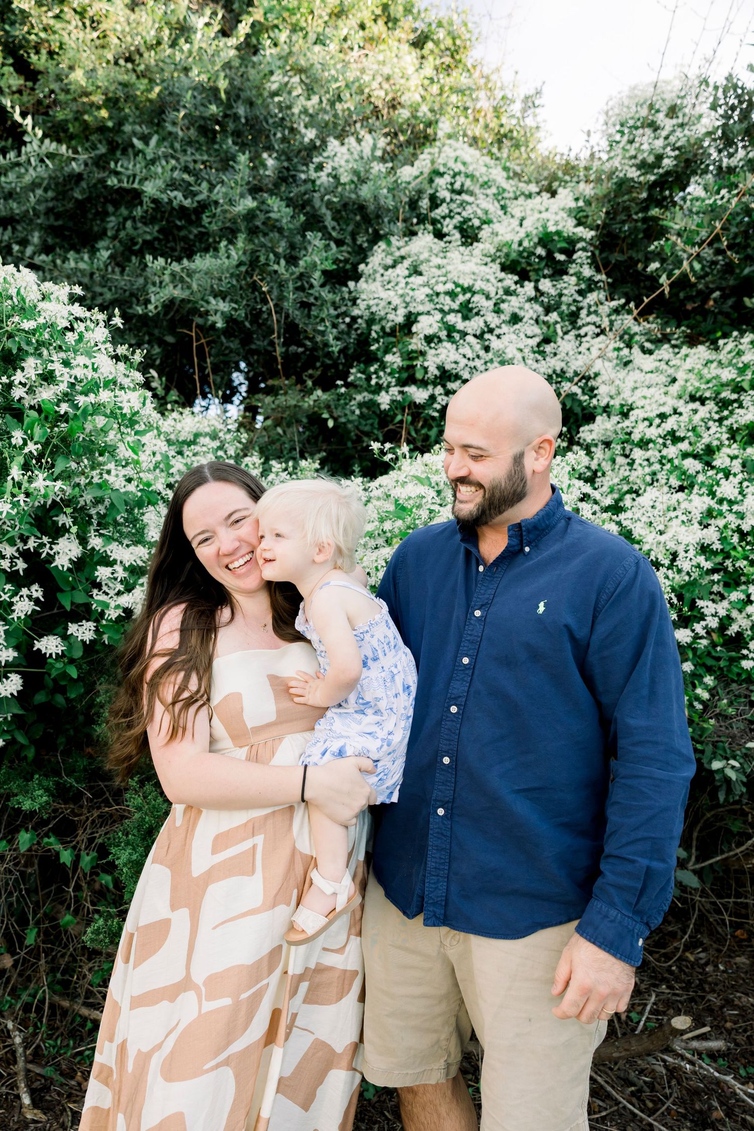 A family enjoying a tender moment together against lush green foliage.
