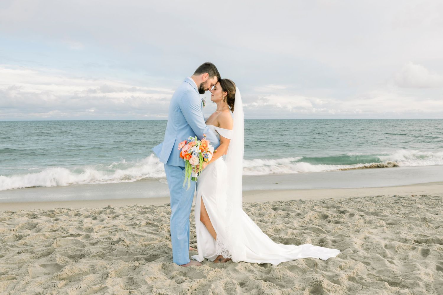 Romantic beach wedding photos with soft coastal colors and ocean waves in background.