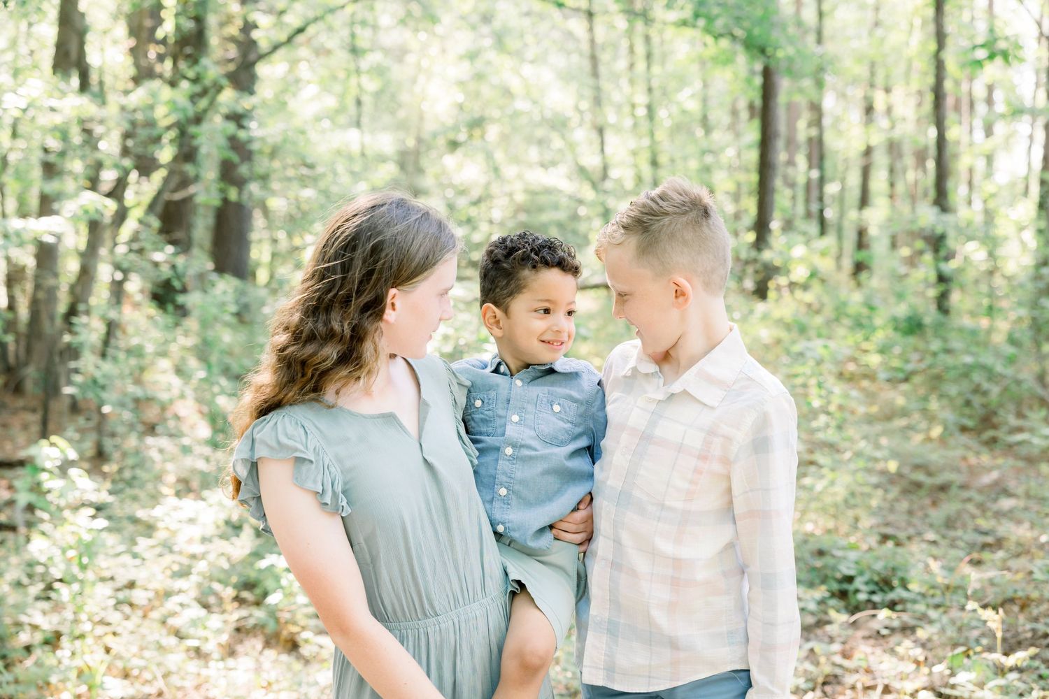 Family portrait session in lush green forest setting during golden hour.