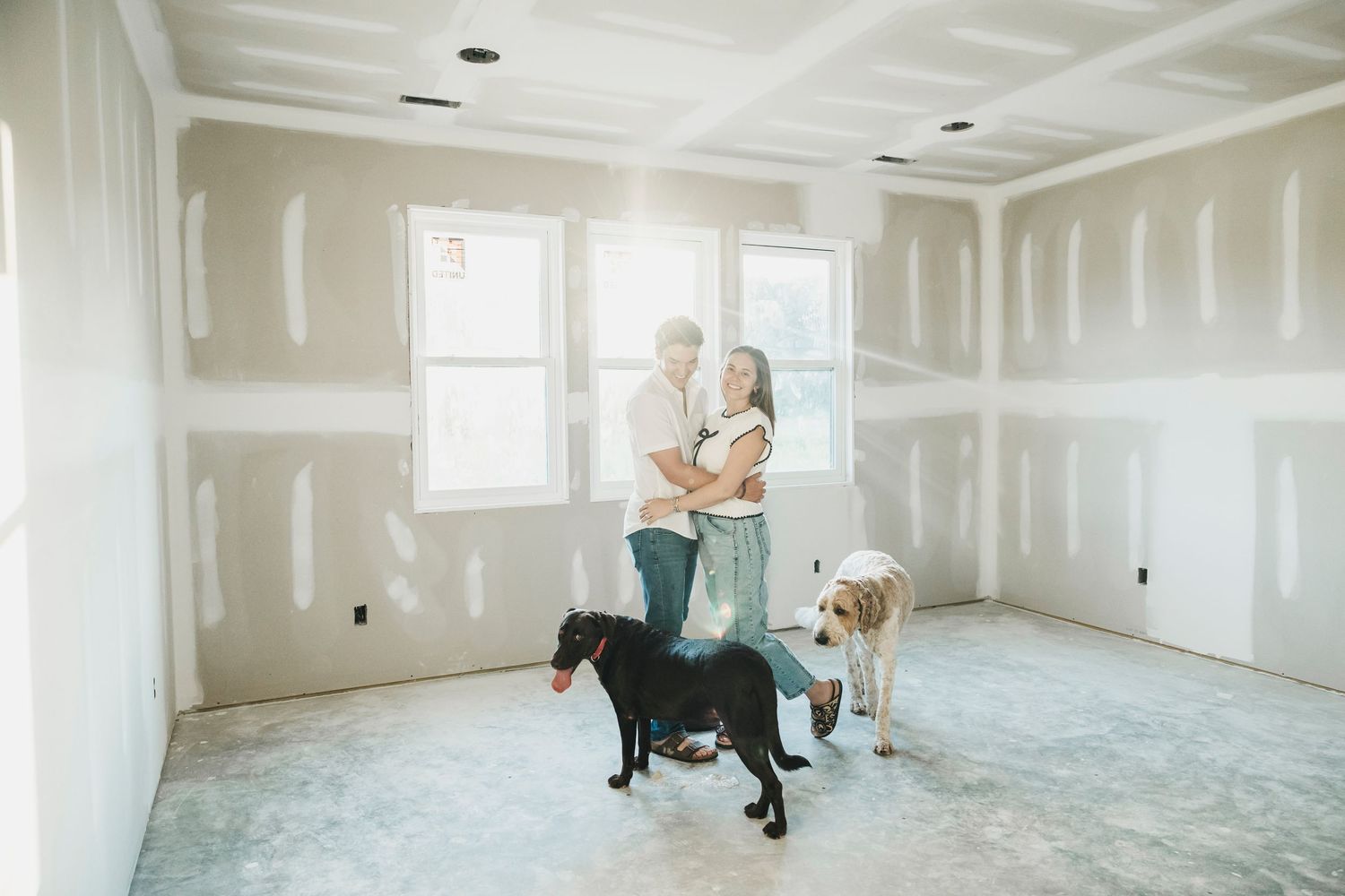 Empty room with white drywall and unfinished floors under construction.