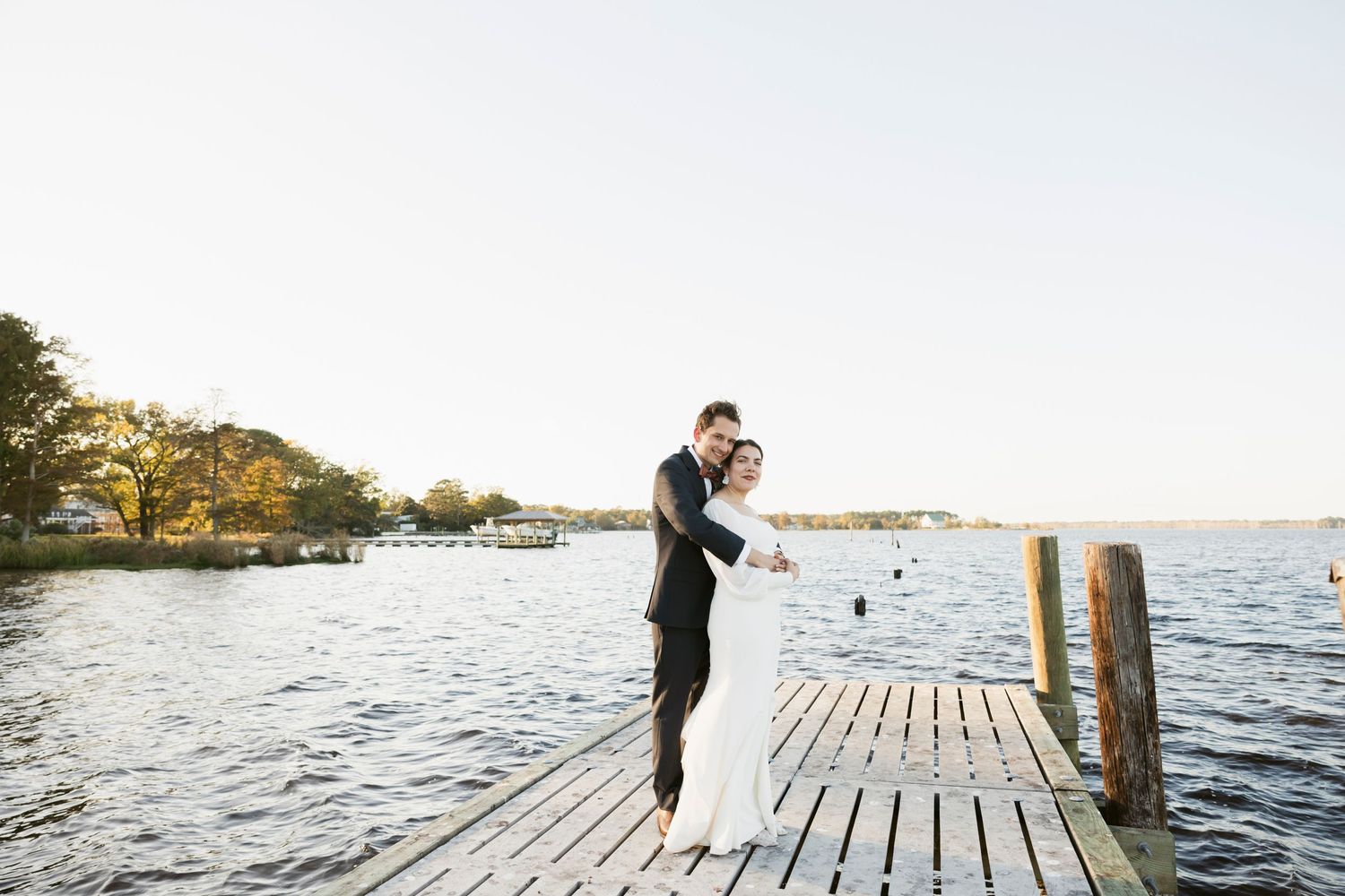 Romantic couple portraits on a wooden dock by the water at sunset.