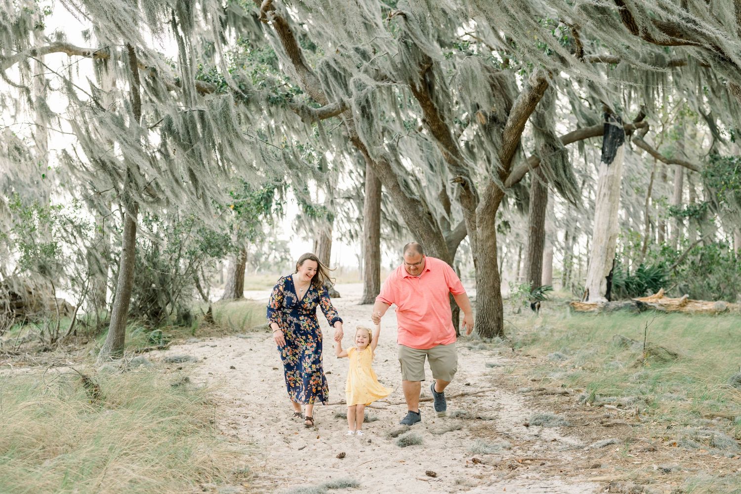 Group walking beneath moss-draped oak trees in a scenic outdoor setting.