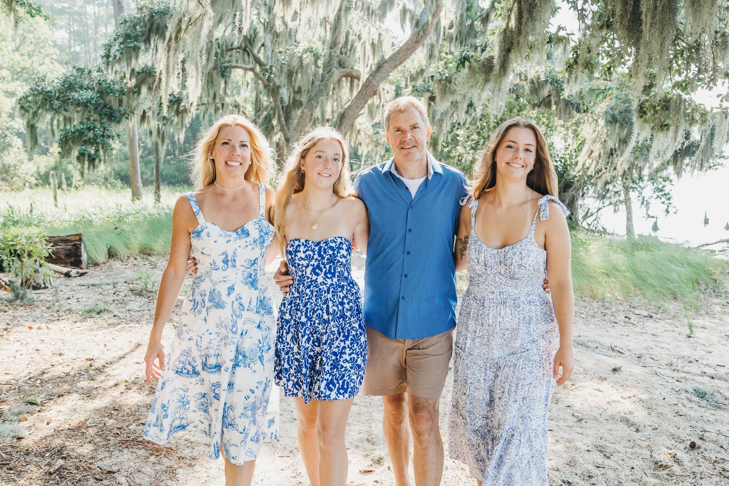 Family group walking together along a tree-lined path wearing coordinated blue and white outfits.