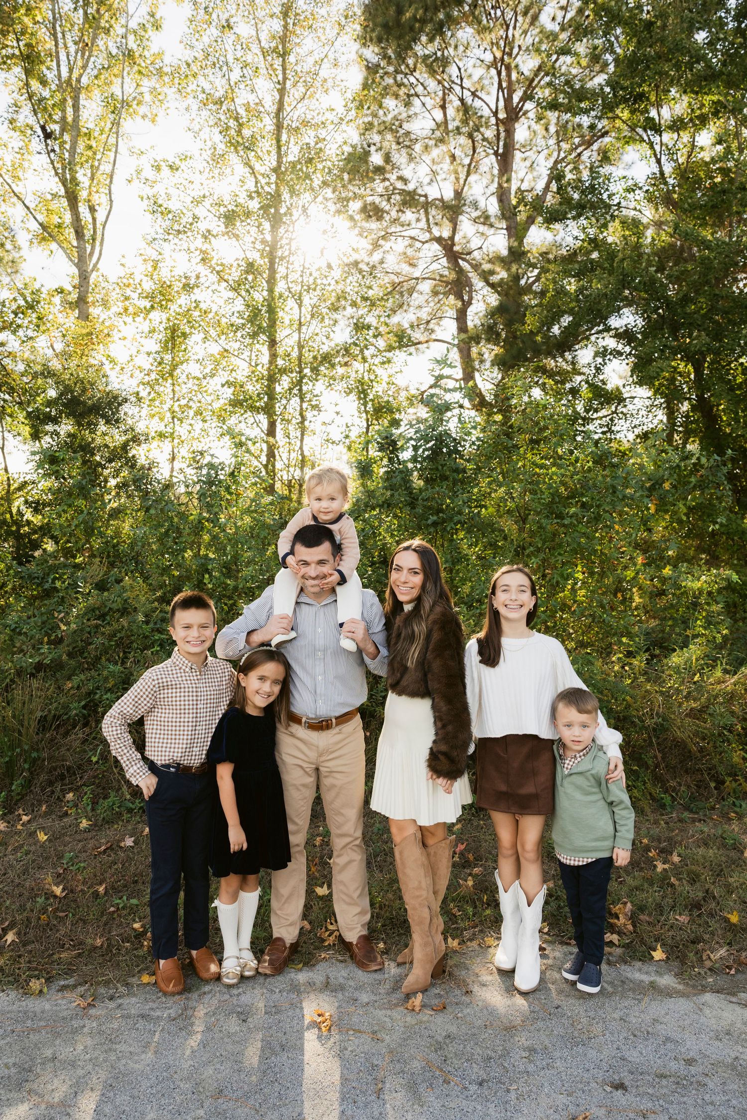 Casual group portrait of people posing together on a dirt path with trees in background.