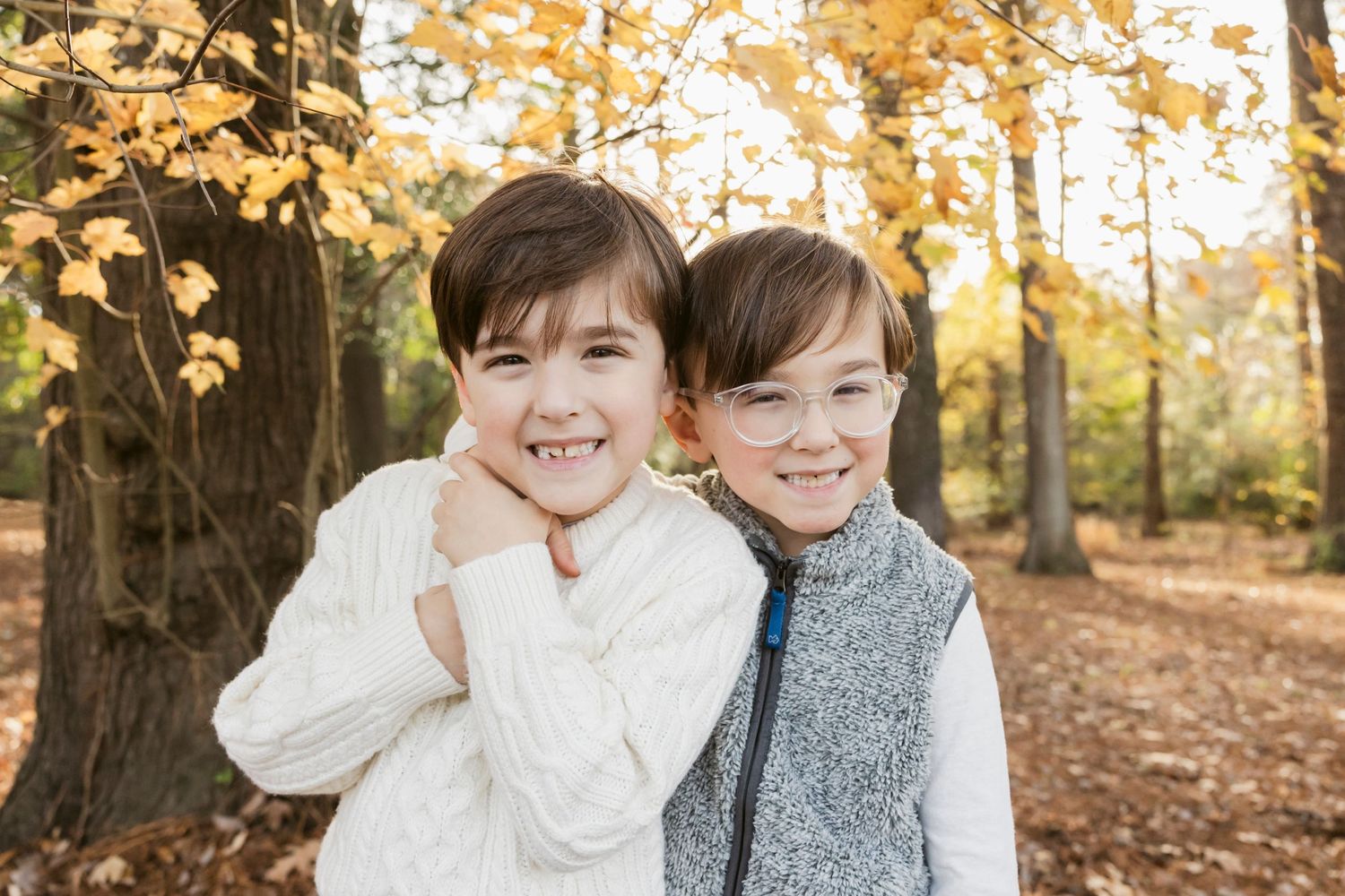 Family portrait session in autumn forest with golden leaves and natural lighting.