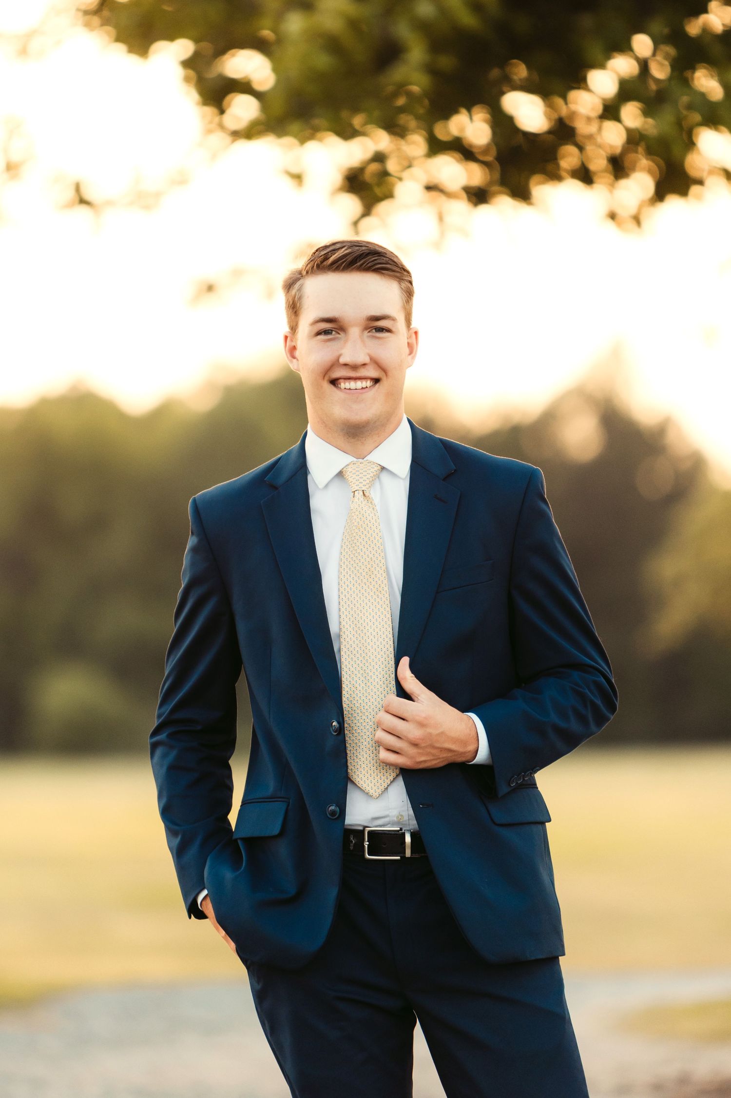 Professional portrait of someone in navy suit and yellow tie during sunset.