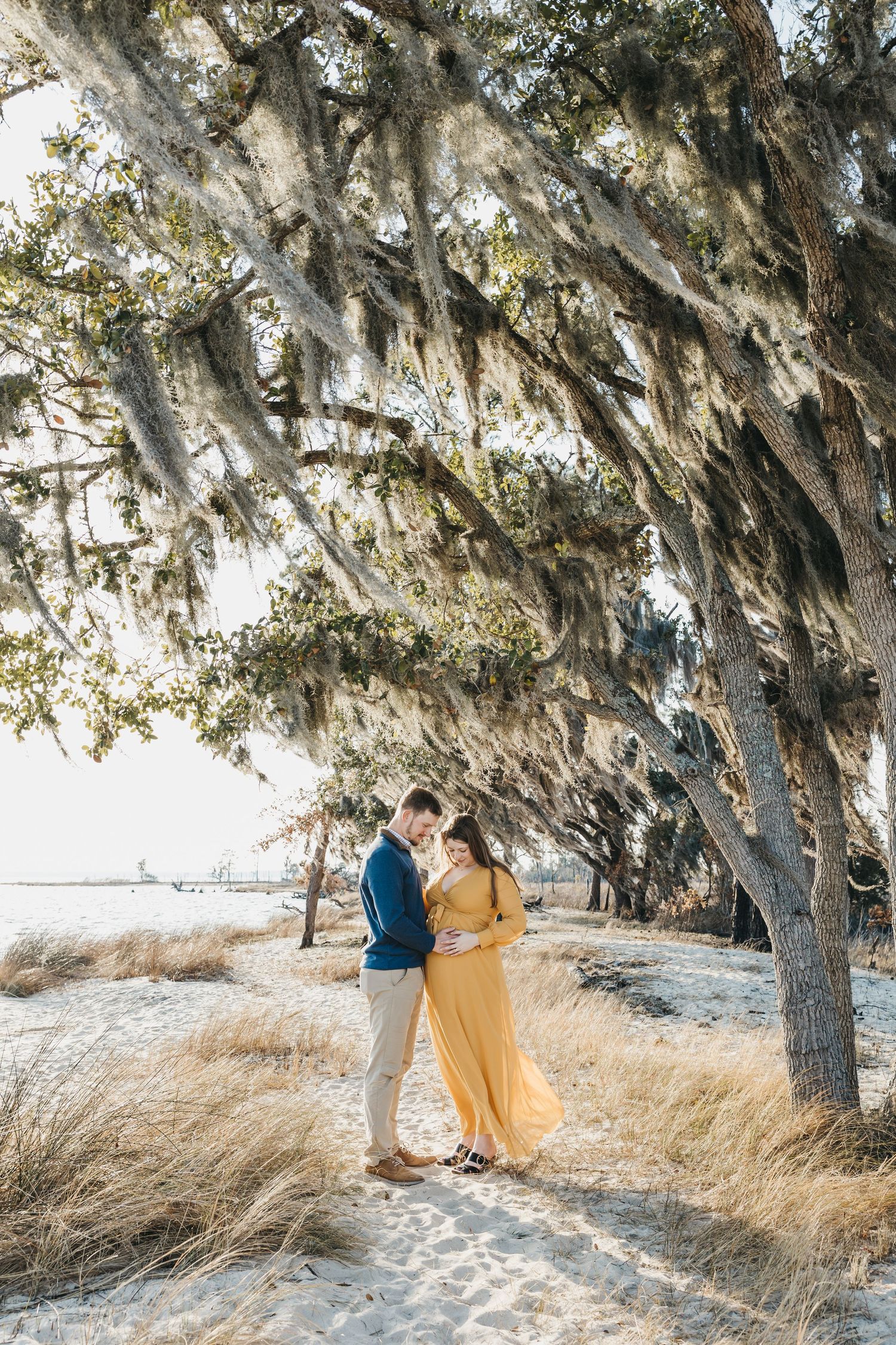 A romantic coastal photoshoot under oak trees with Spanish moss and golden light.