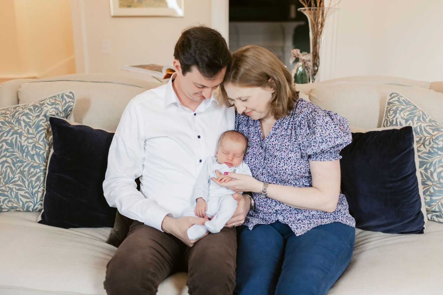 Family sitting together on couch during lifestyle newborn photography session.